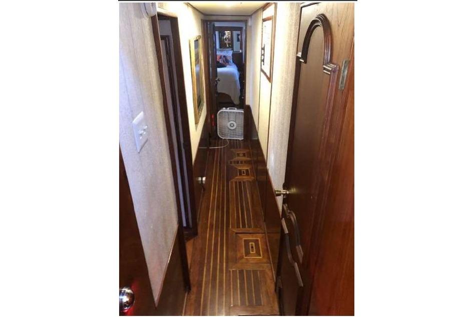 Narrow hallway inside a 1974 Pacemaker Cockpit Motoryacht with wooden flooring and doors.