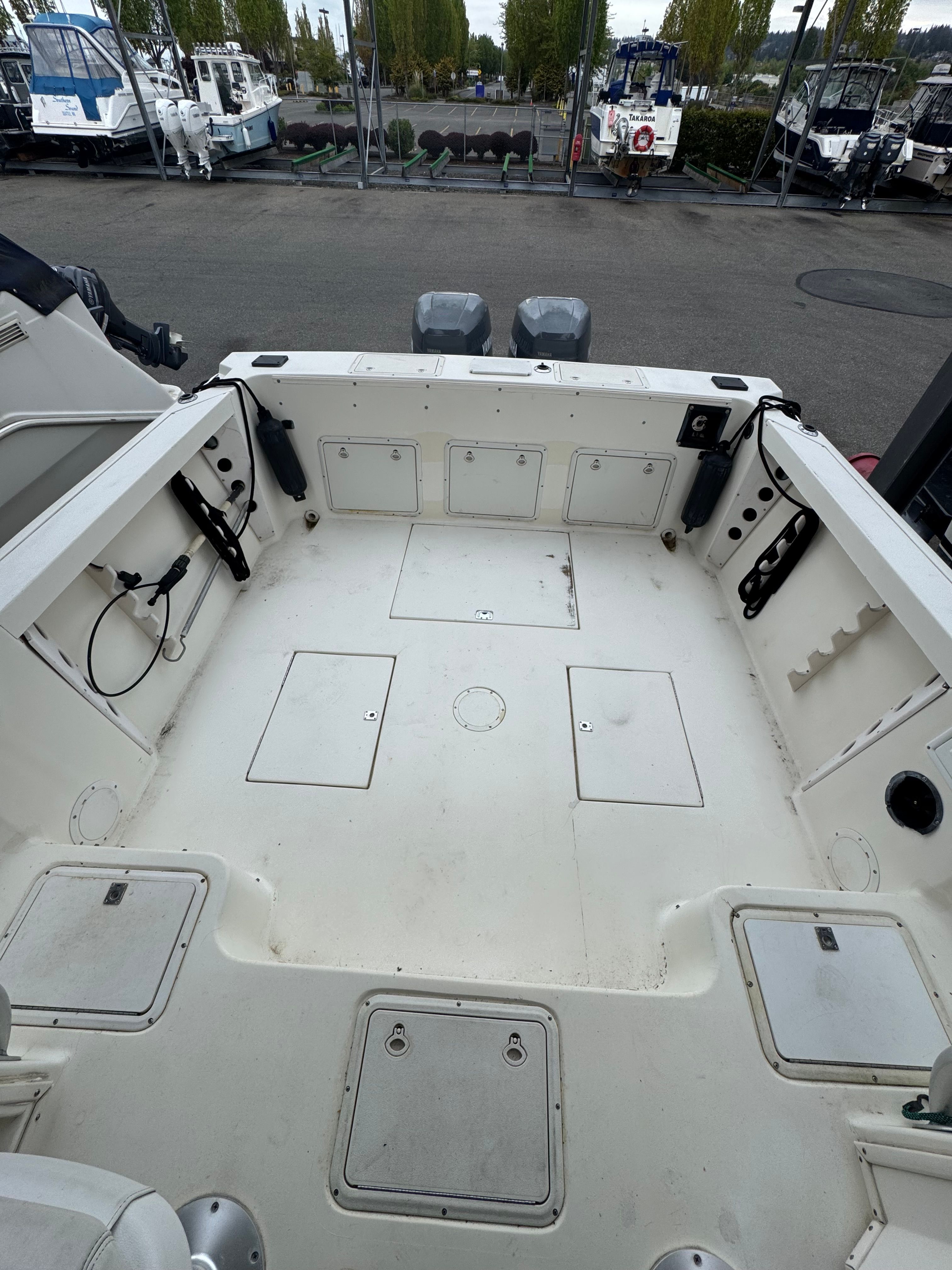 The boat features a spacious deck with multiple storage compartments and two outboard motors.