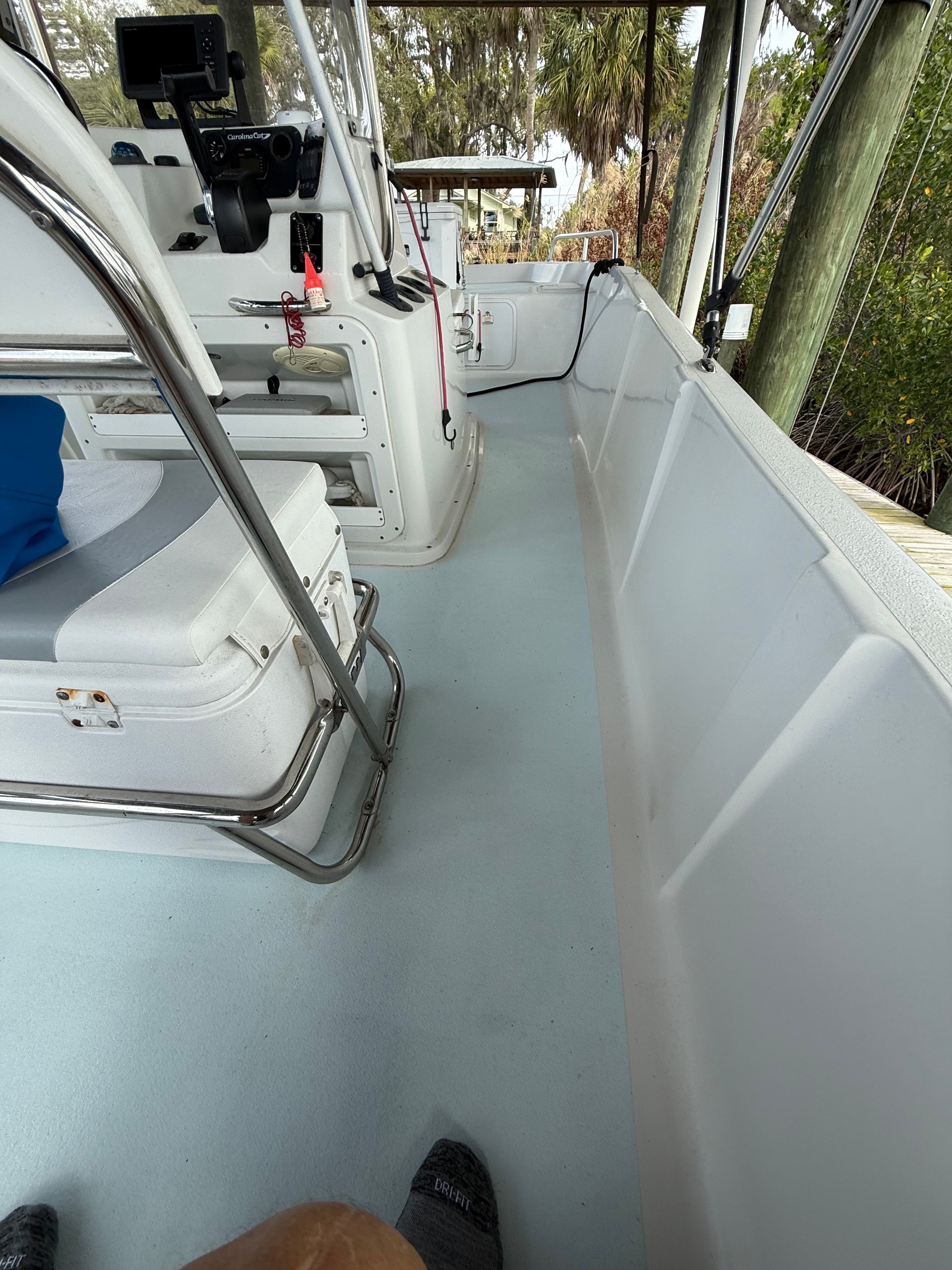 Interior view of a boat with white seats and a steering console.
