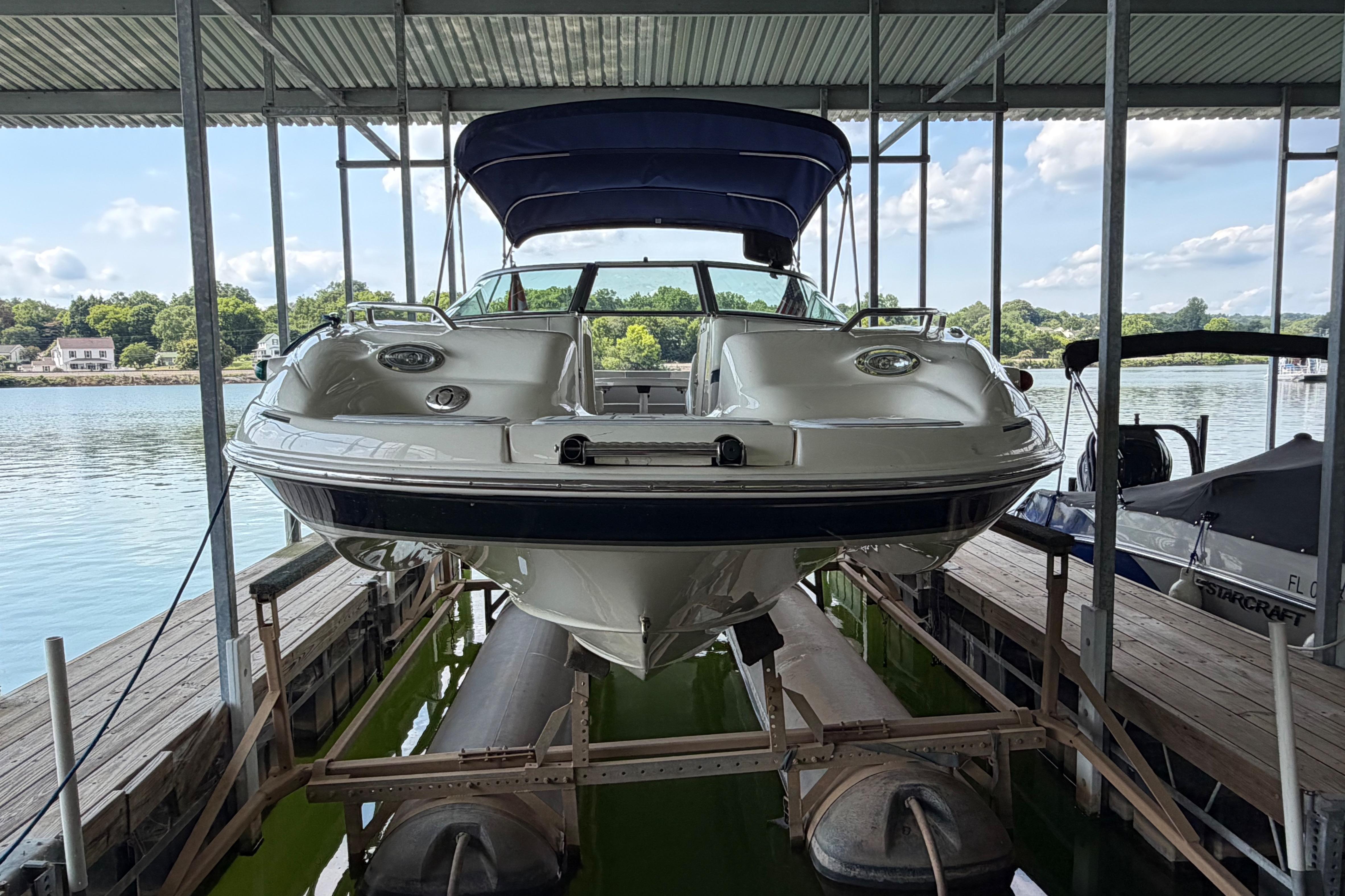 2010 Bryant 255 boat docked under a covered marina with scenic lake view.