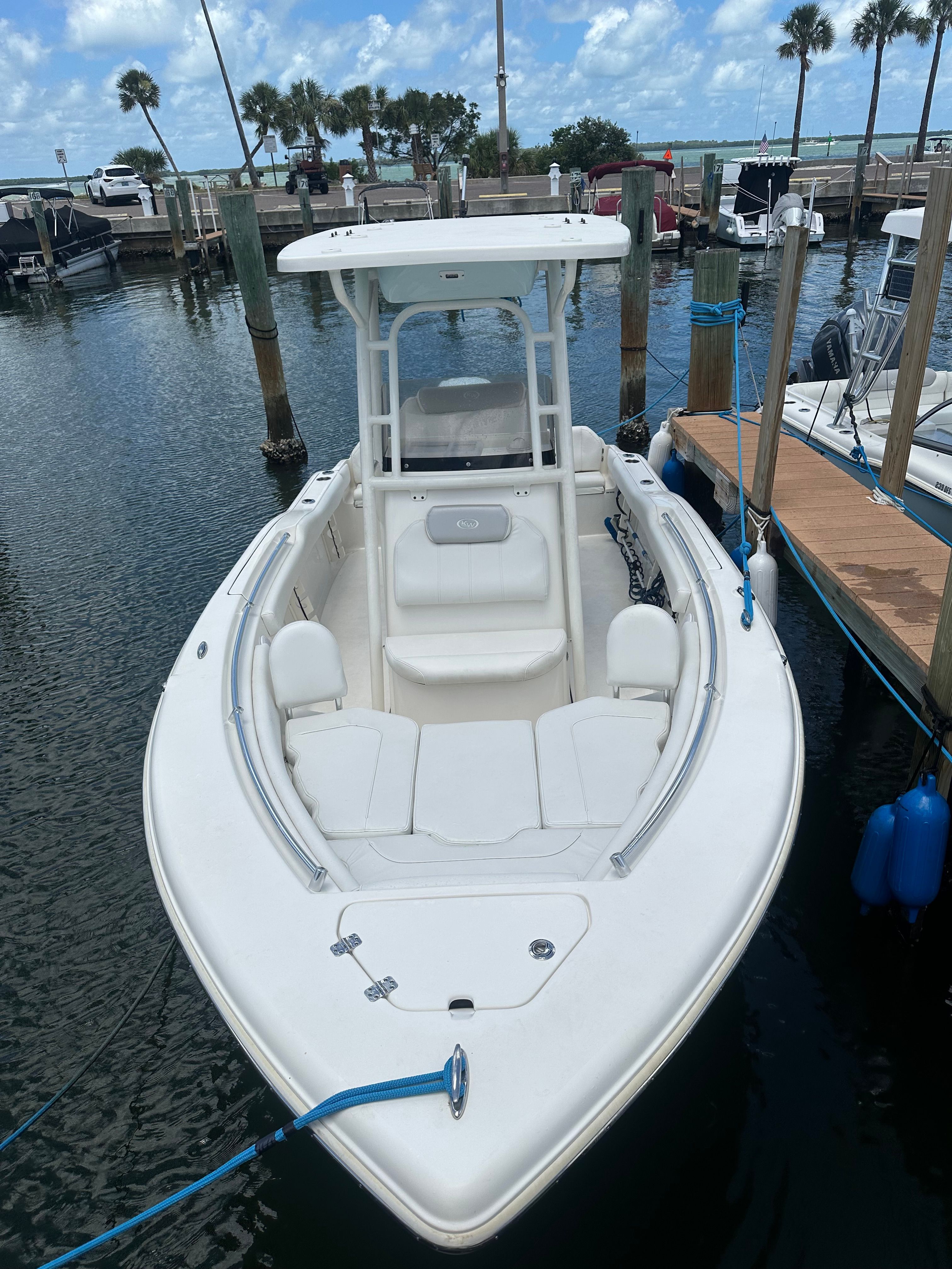 A white boat docked, surrounded by water and palm trees.
