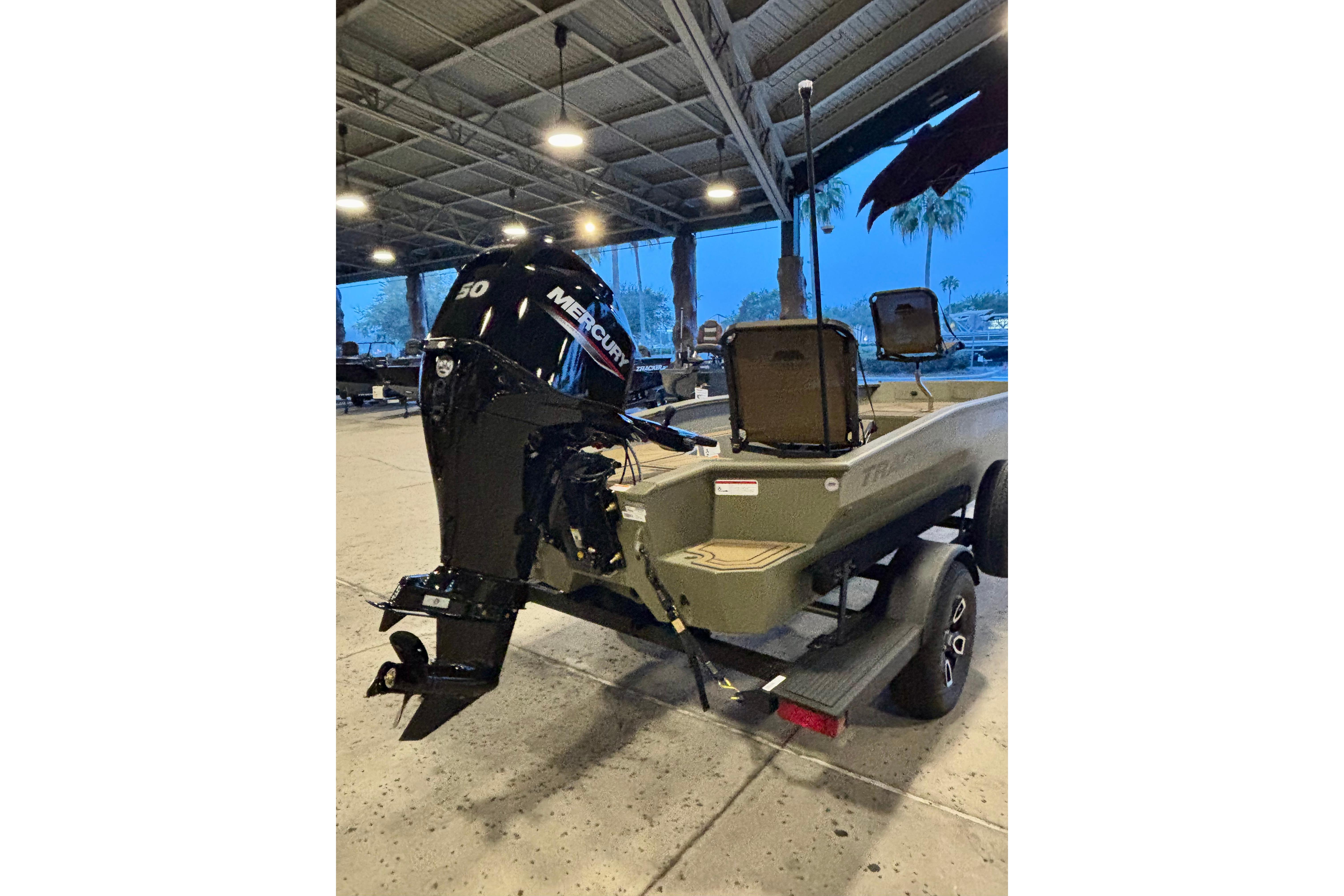 2026 Tracker Grizzly 1650 T Prairie Wings Edition boat with Mercury 50 engine in a garage.