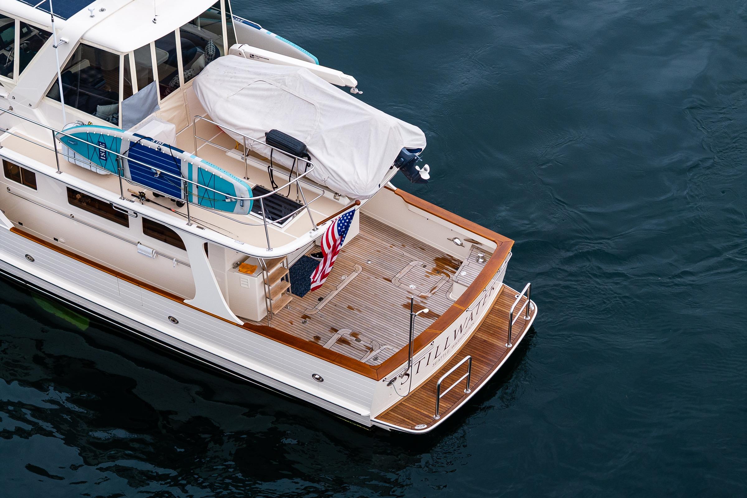 2026 Fleming 55 Pilothouse yacht with surfboards and American flag on deck.