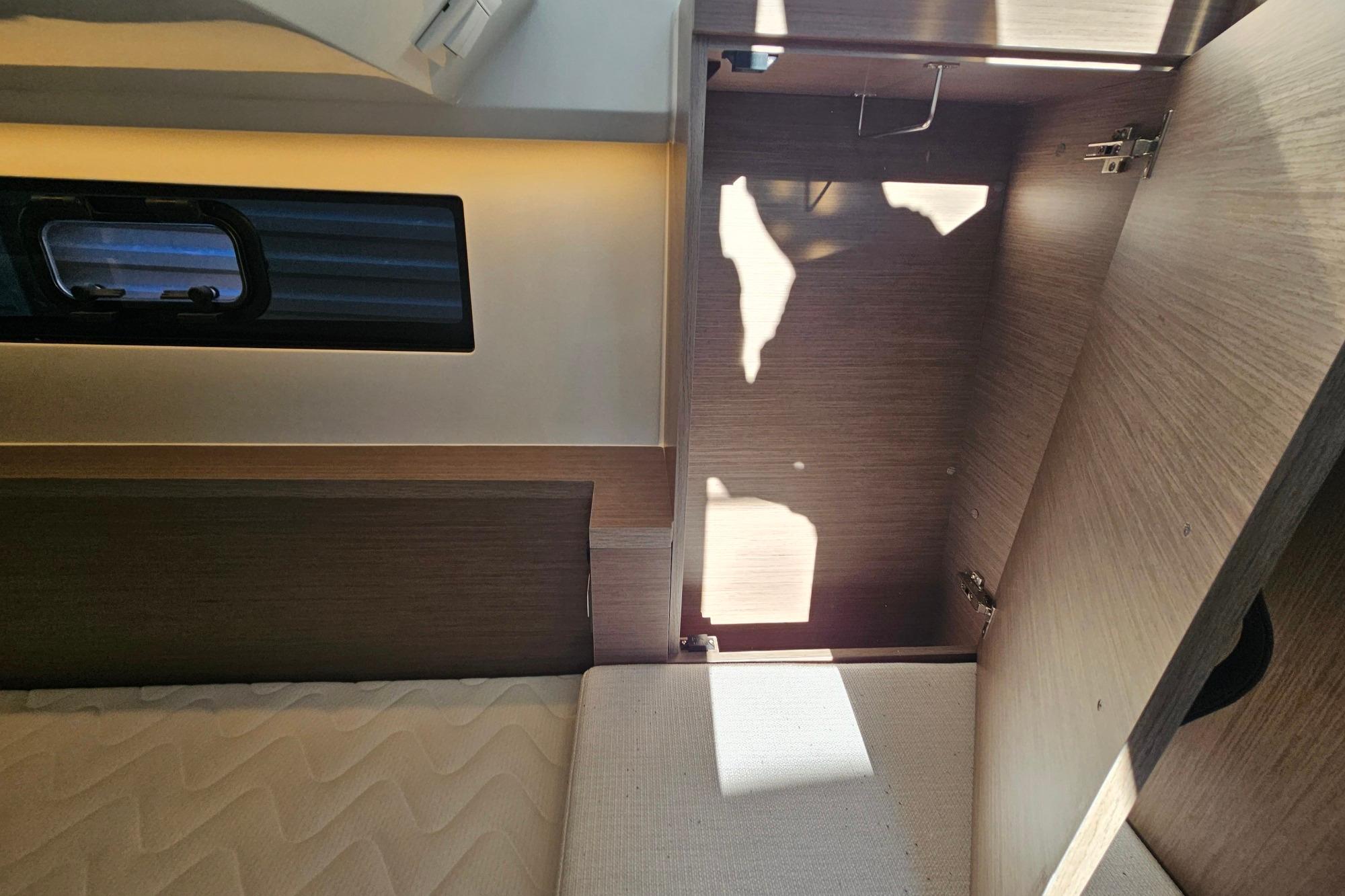 Interior of 2026 Jeanneau Merry Fisher 1095 Fly Serie 2, featuring wood cabinetry and window.