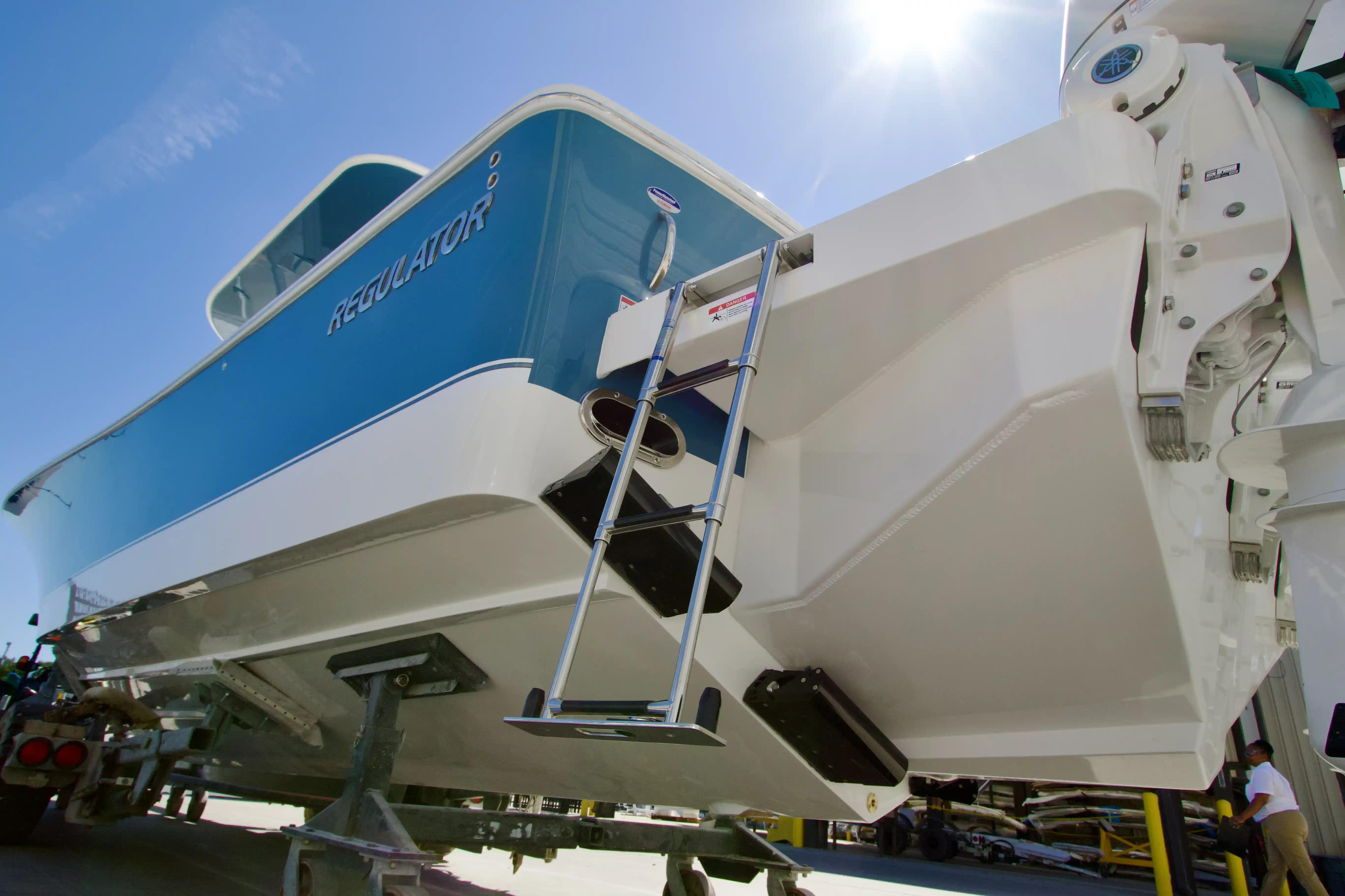 2027 Regulator 35 boat with blue and white hull, ladder, and sunny sky background.