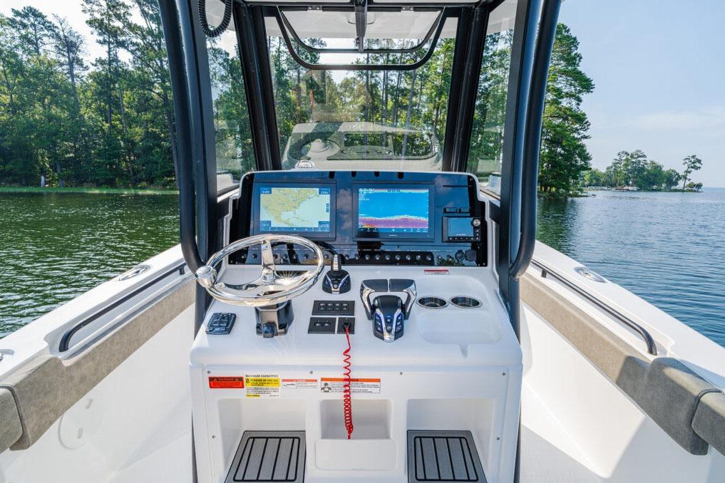 Manufacturer Provided Image: 2026 Sea Hunt Gamefish 25 boat dashboard with navigation screens and steering wheel on a lake.
