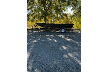 2026 Tracker Grizzly 1754 Utility boat on trailer, parked under trees.