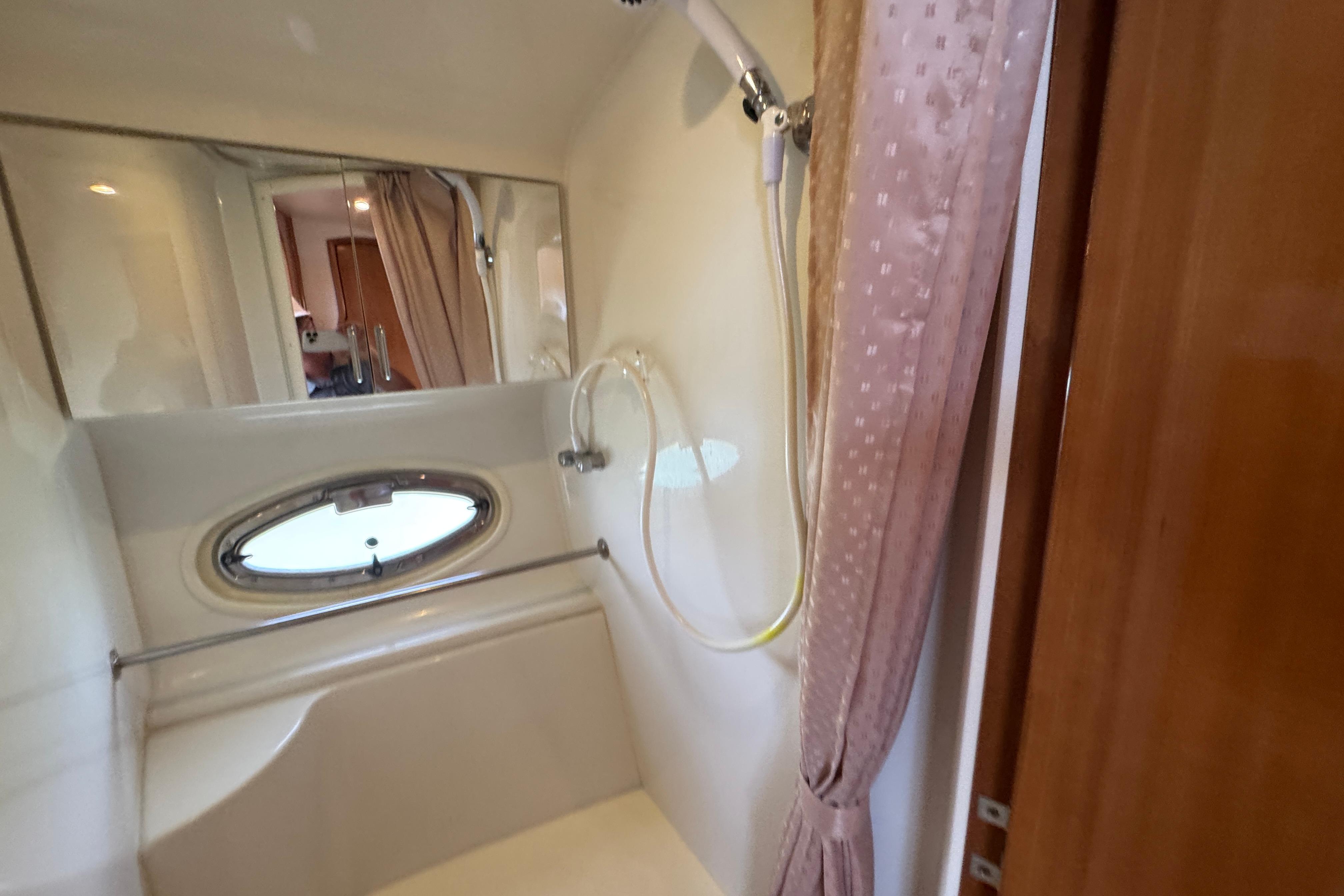 Shower area in 2002 Carver 396 Motor Yacht with oval window and curtain.