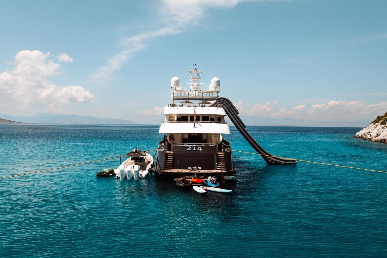Luxury yacht Ortona Navi 2008 anchored with slide and water toys in clear blue sea.