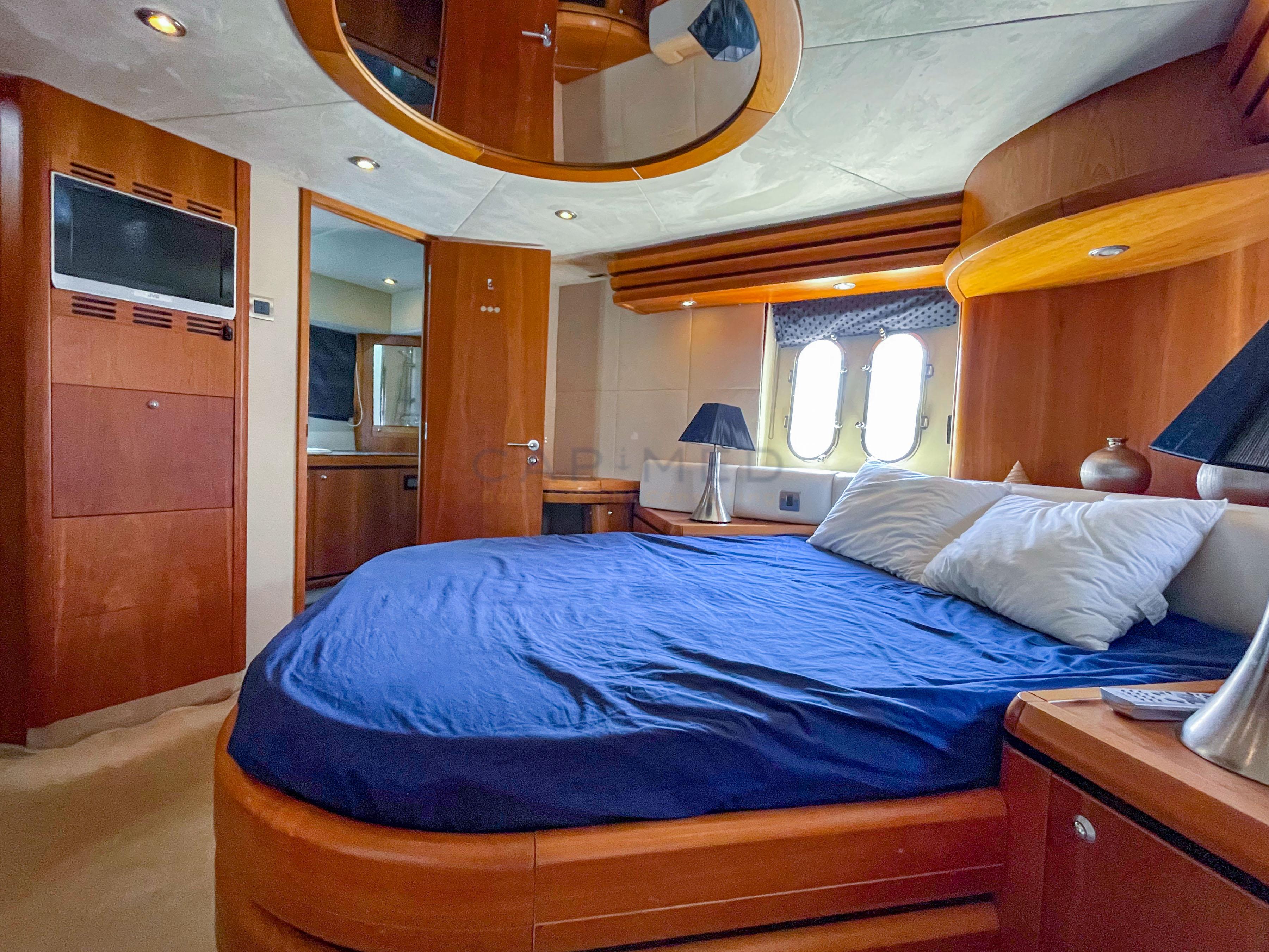 Luxurious bedroom interior of 2006 Pearl 60 yacht with wooden furnishings and blue bedding.