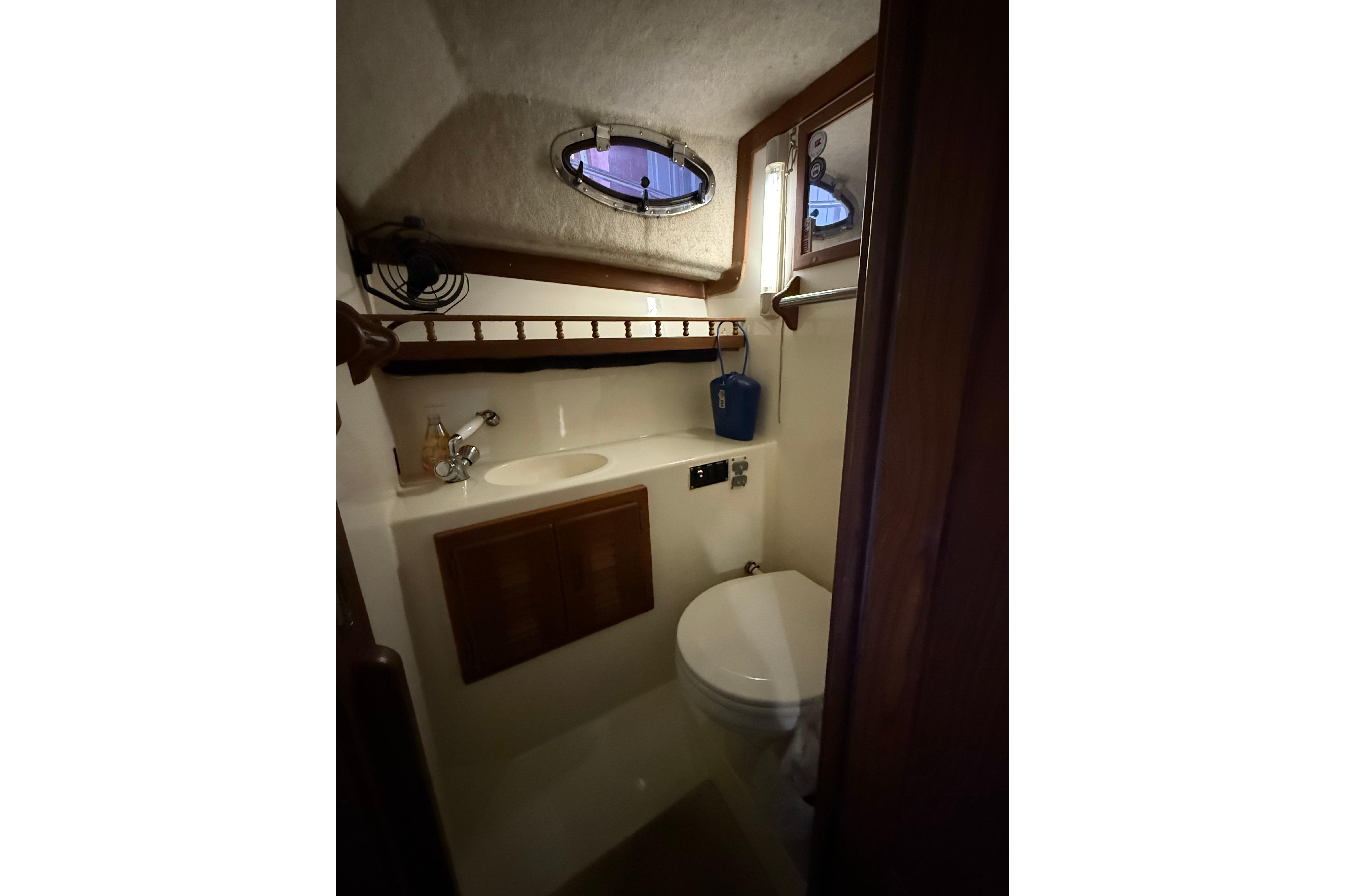 2002 Albemarle 265 Express Fisherman boat bathroom with sink, toilet, and porthole window.