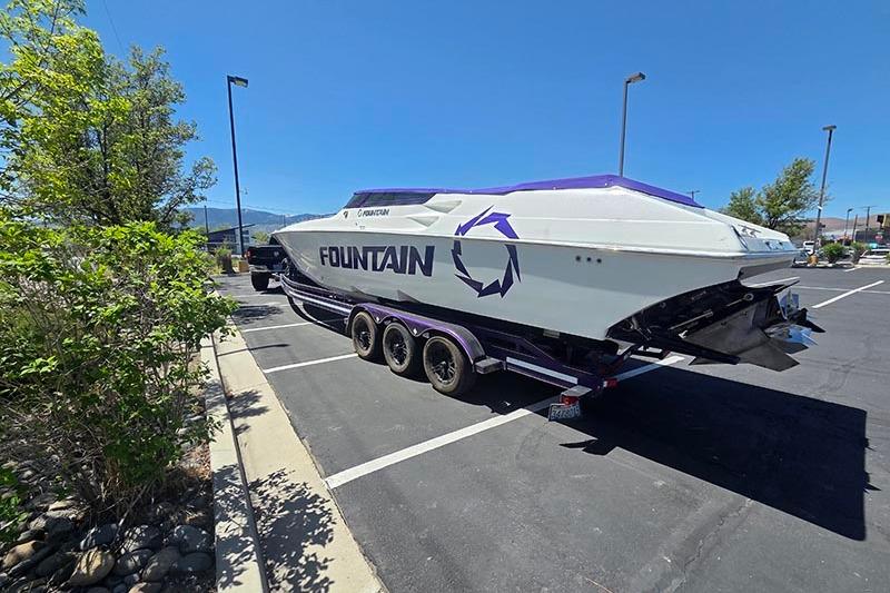 2004 Fountain 38 Lightning boat on trailer in parking lot under clear blue sky.