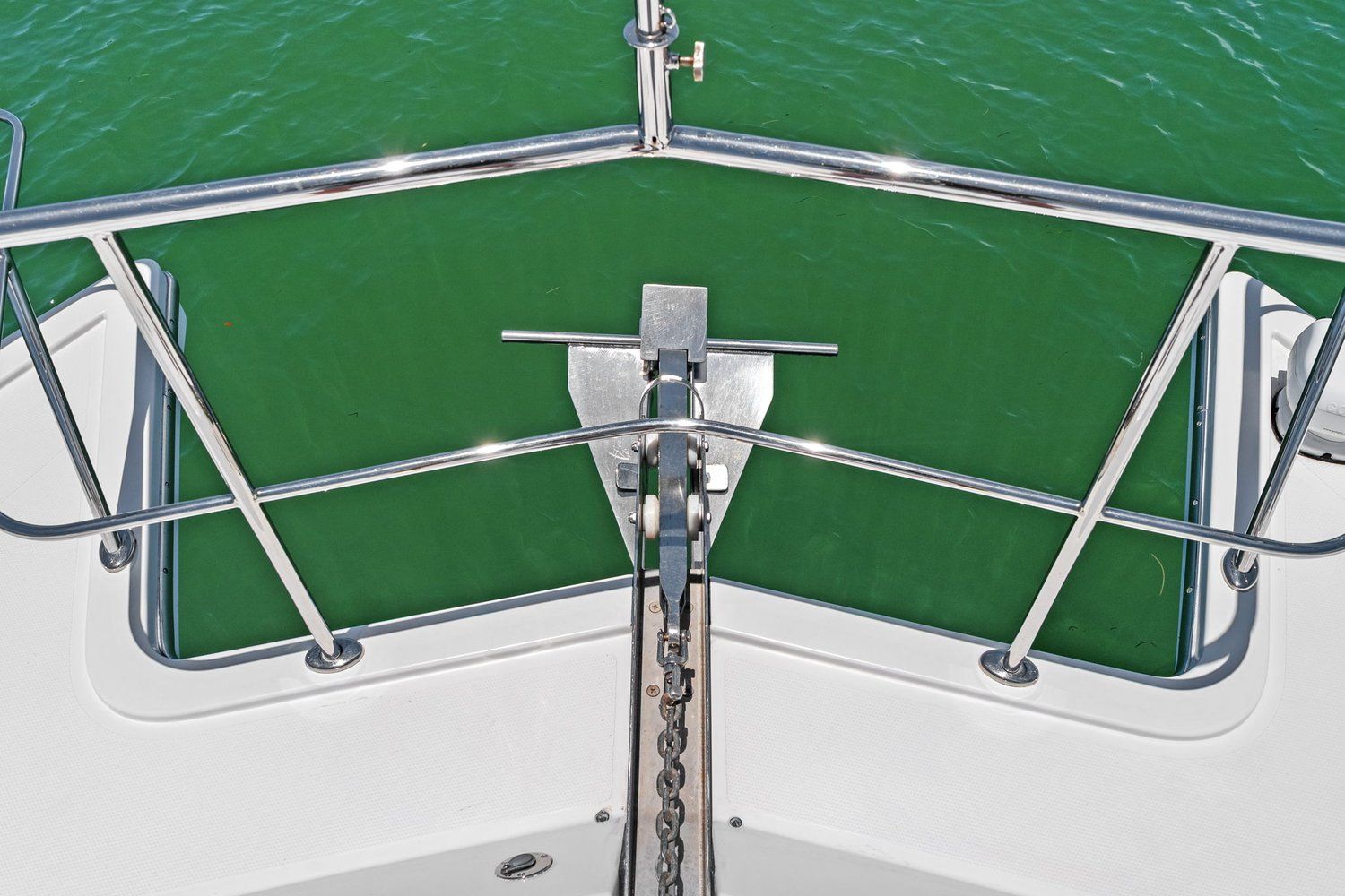 Bow view of a catamaran with stainless steel railing and anchor over green water.