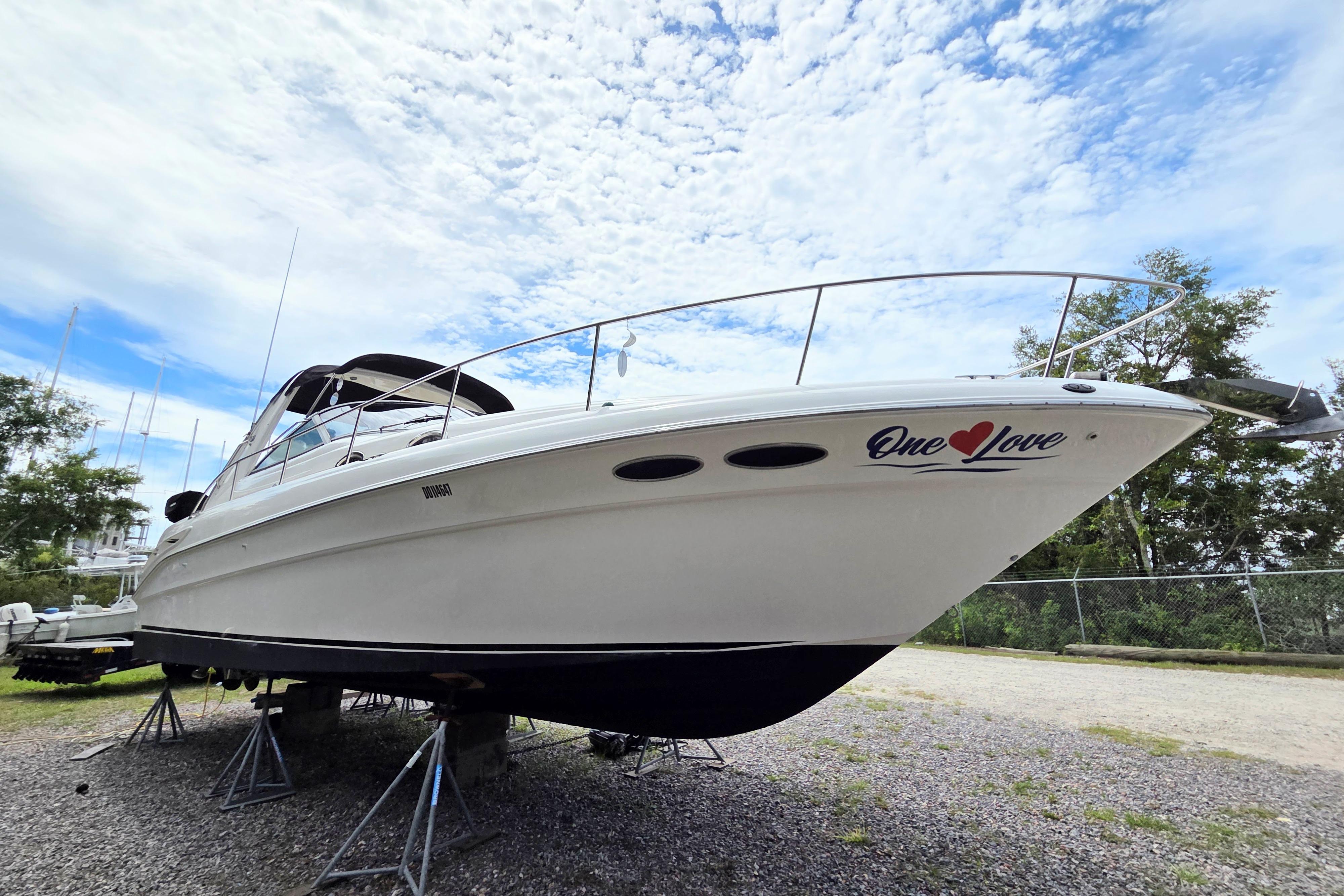 2000 Sea Ray 340 Sundancer boat named "One Love" on stands, under a partly cloudy sky.