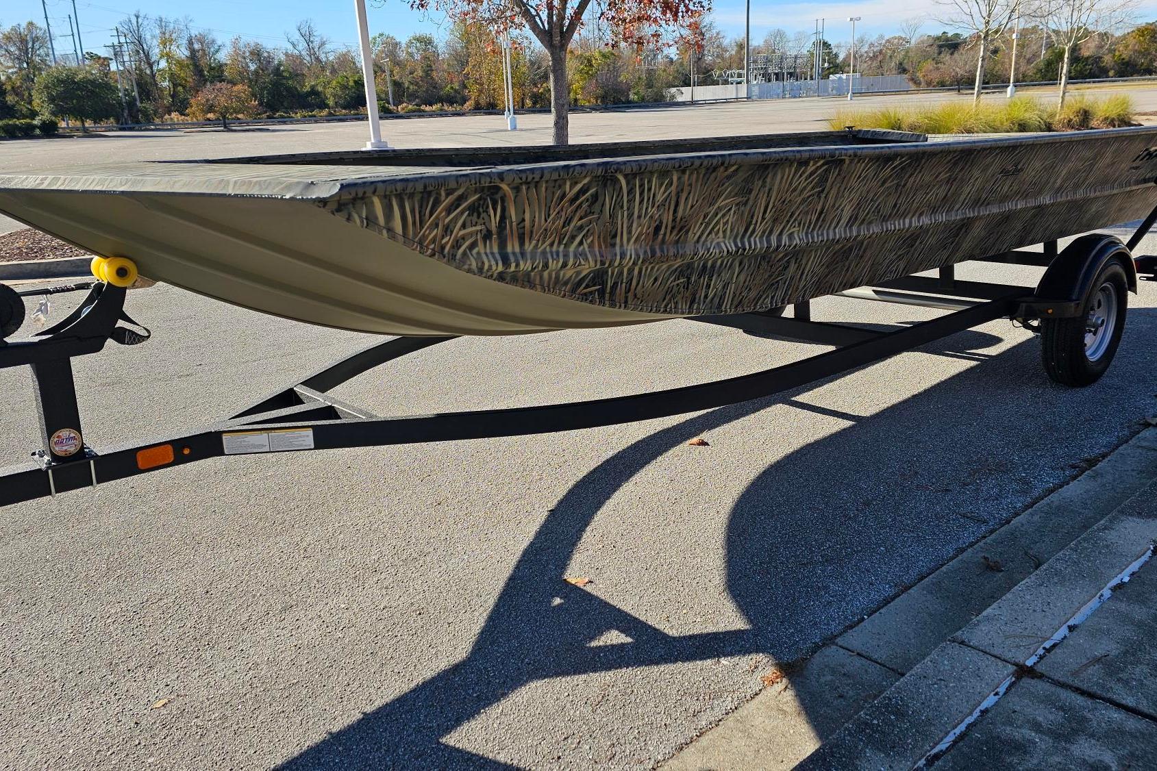 2025 Tracker Grizzly 1860 Utility boat on trailer, parked in sunny lot.