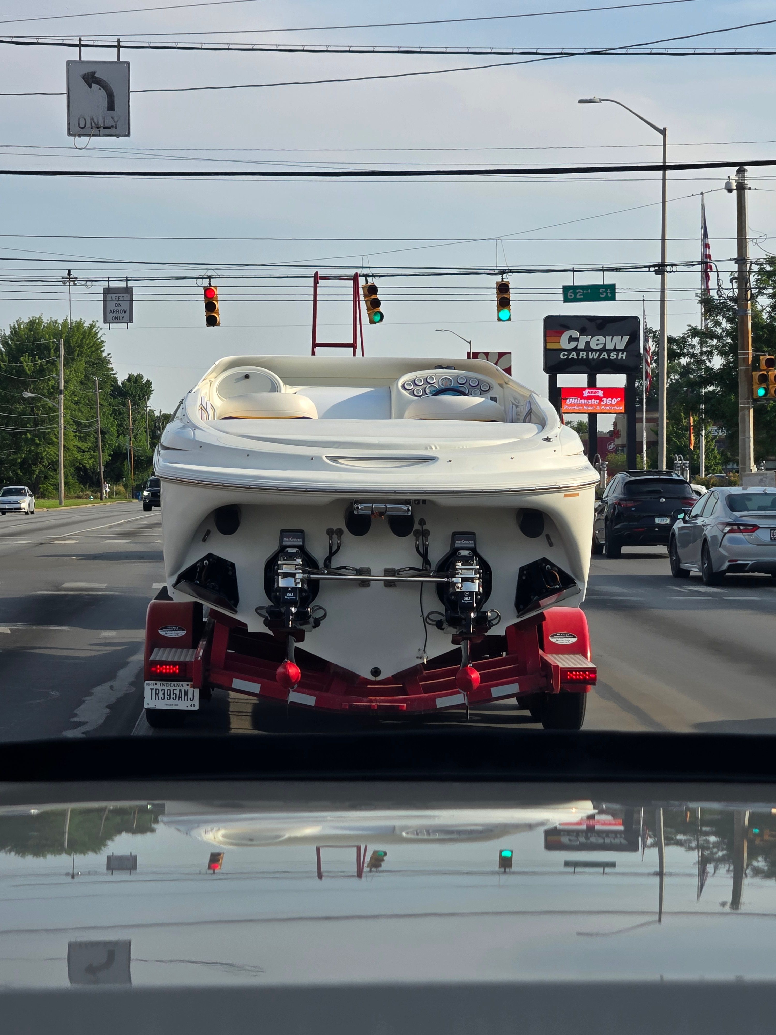 A 1996 Baja 302 Boss boat is being transported on a trailer, on a busy road.