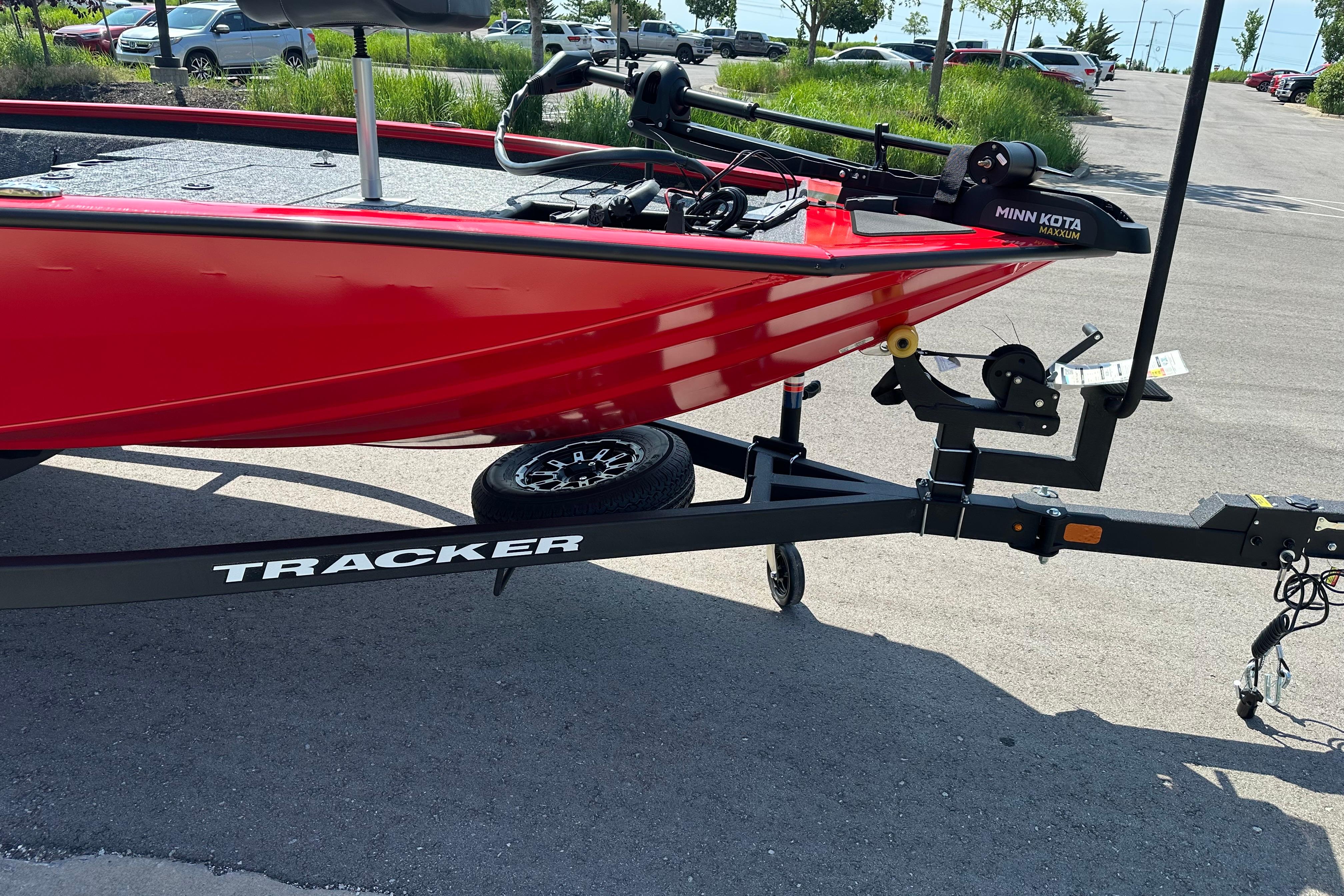 Red 2026 Tracker Pro Team 195 boat on trailer in parking lot.