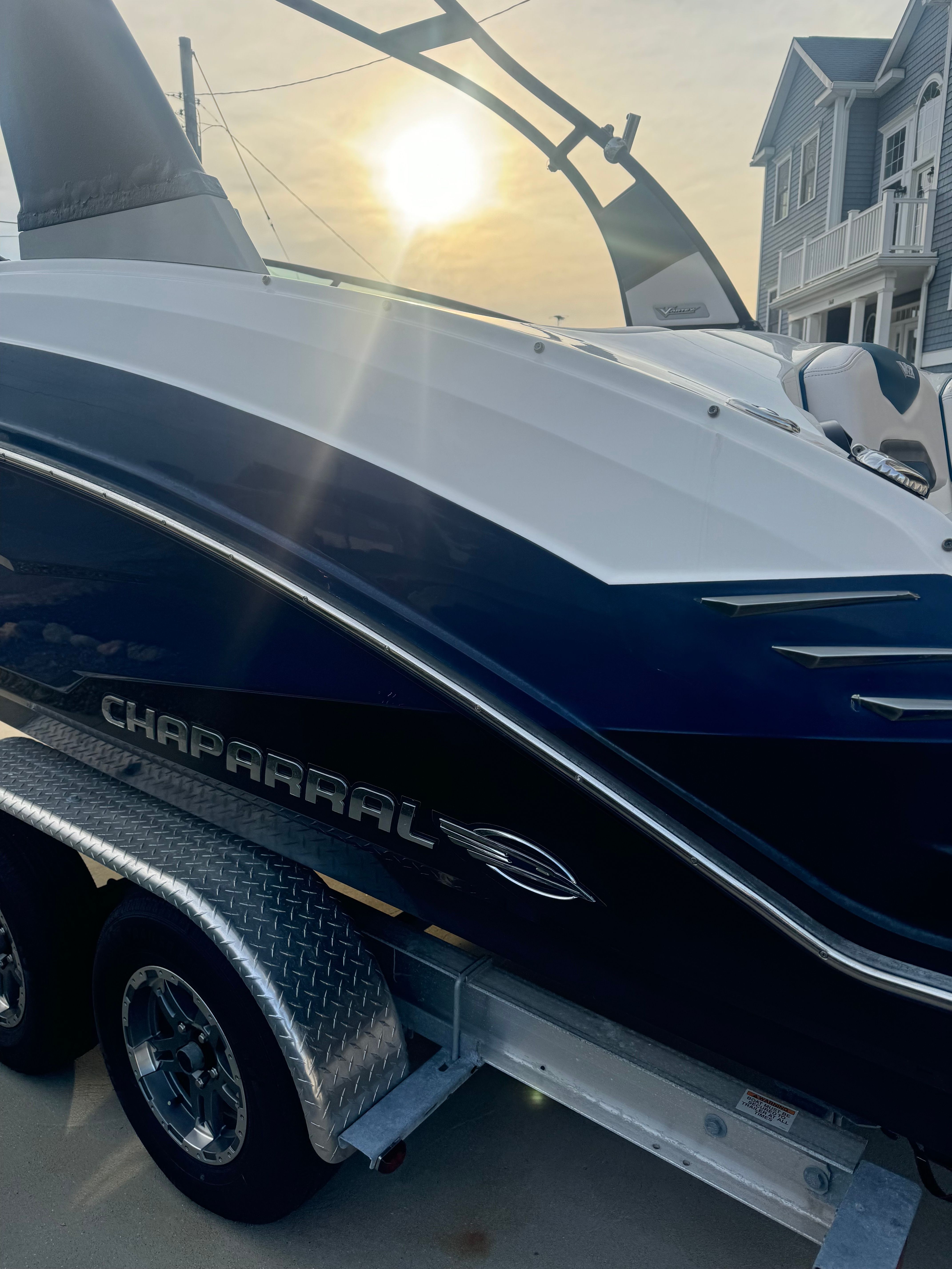 Chaparral Vortex 243 VRX on a trailer at sunset, with modern buildings in the background.
