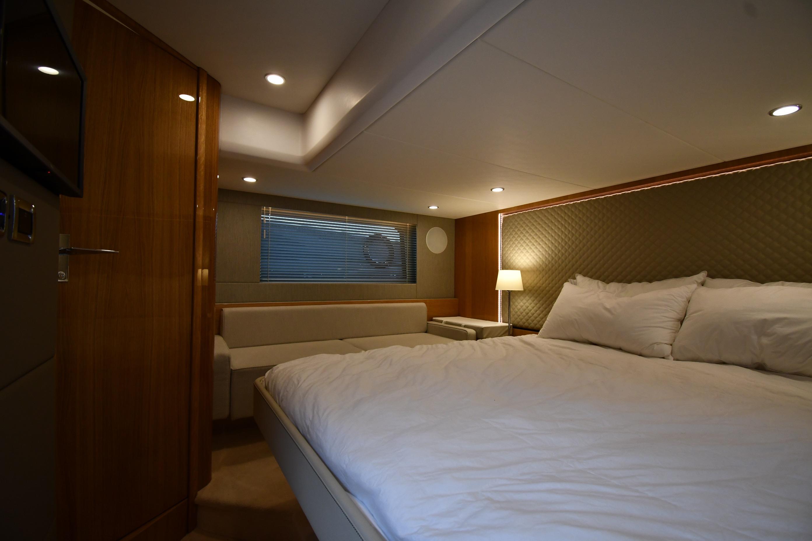 Luxurious cabin interior of 2024 Fairline G50 Targa yacht with cozy bed and ambient lighting.