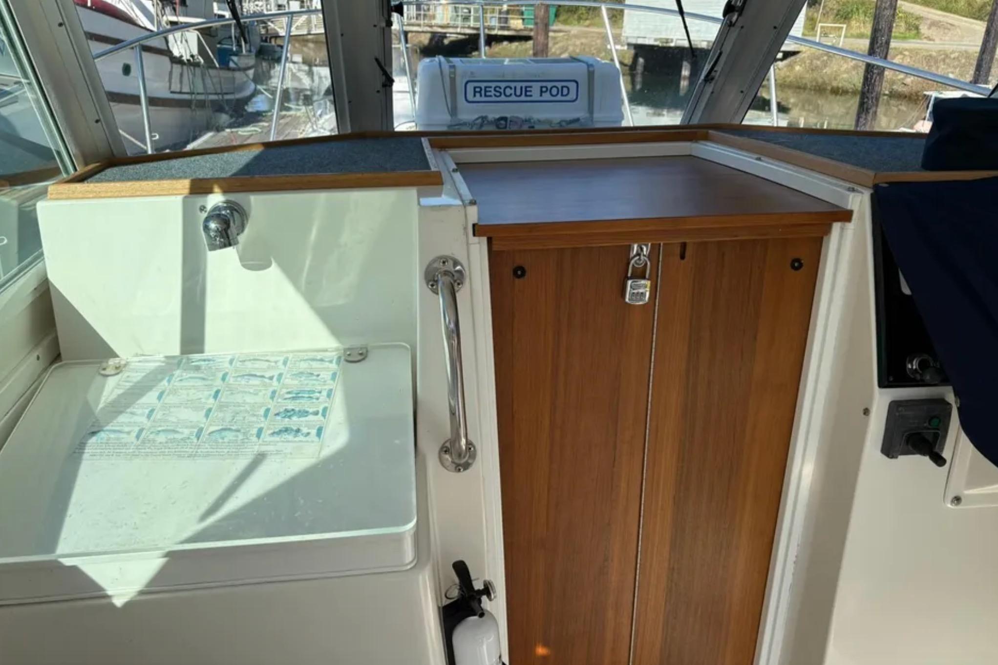 Interior view of a 2005 Albin 28 Tournament Express boat with a wooden cabinet and sink.