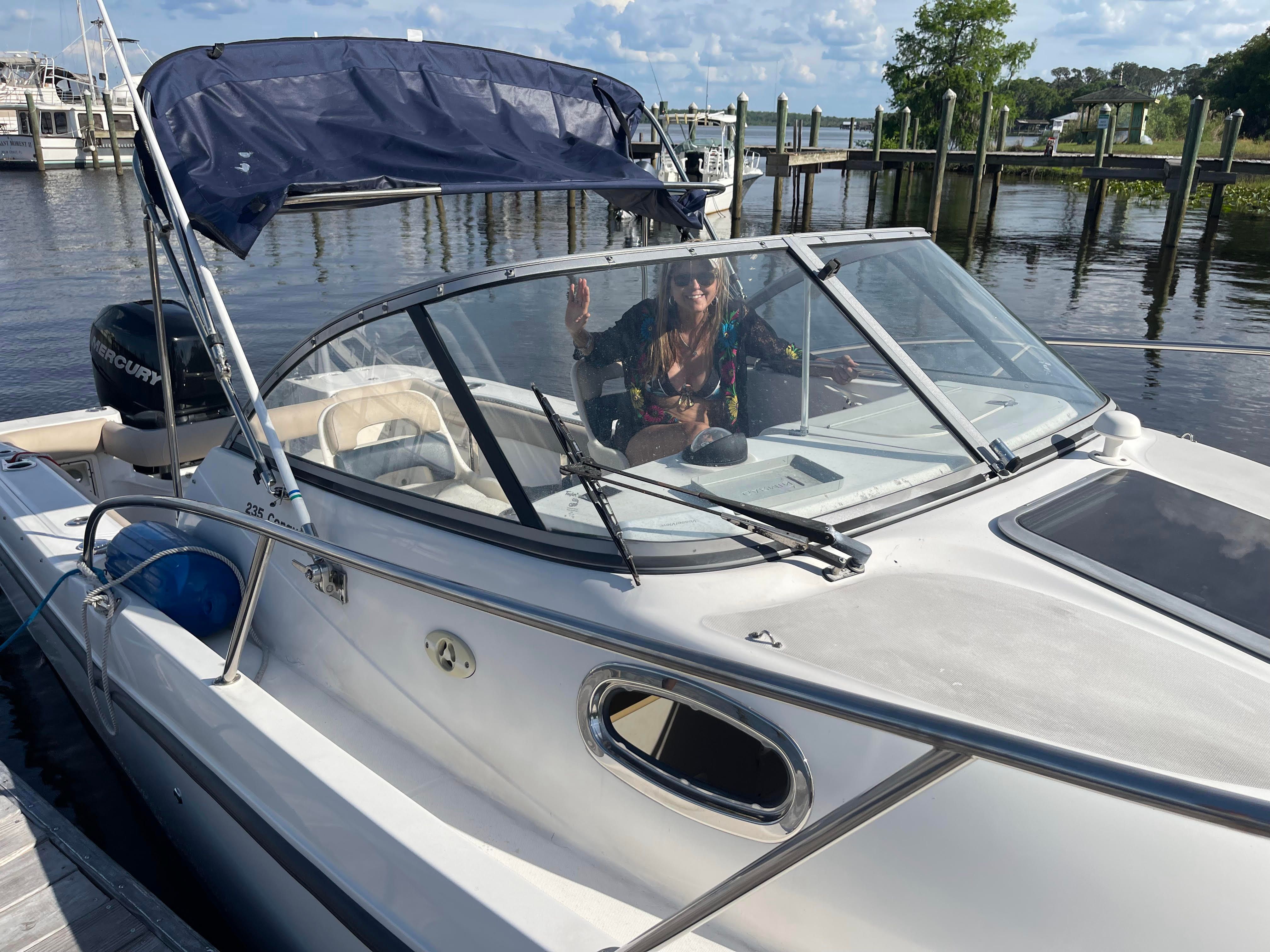2010 Boston Whaler 235 Conquest boat docked with person on board.