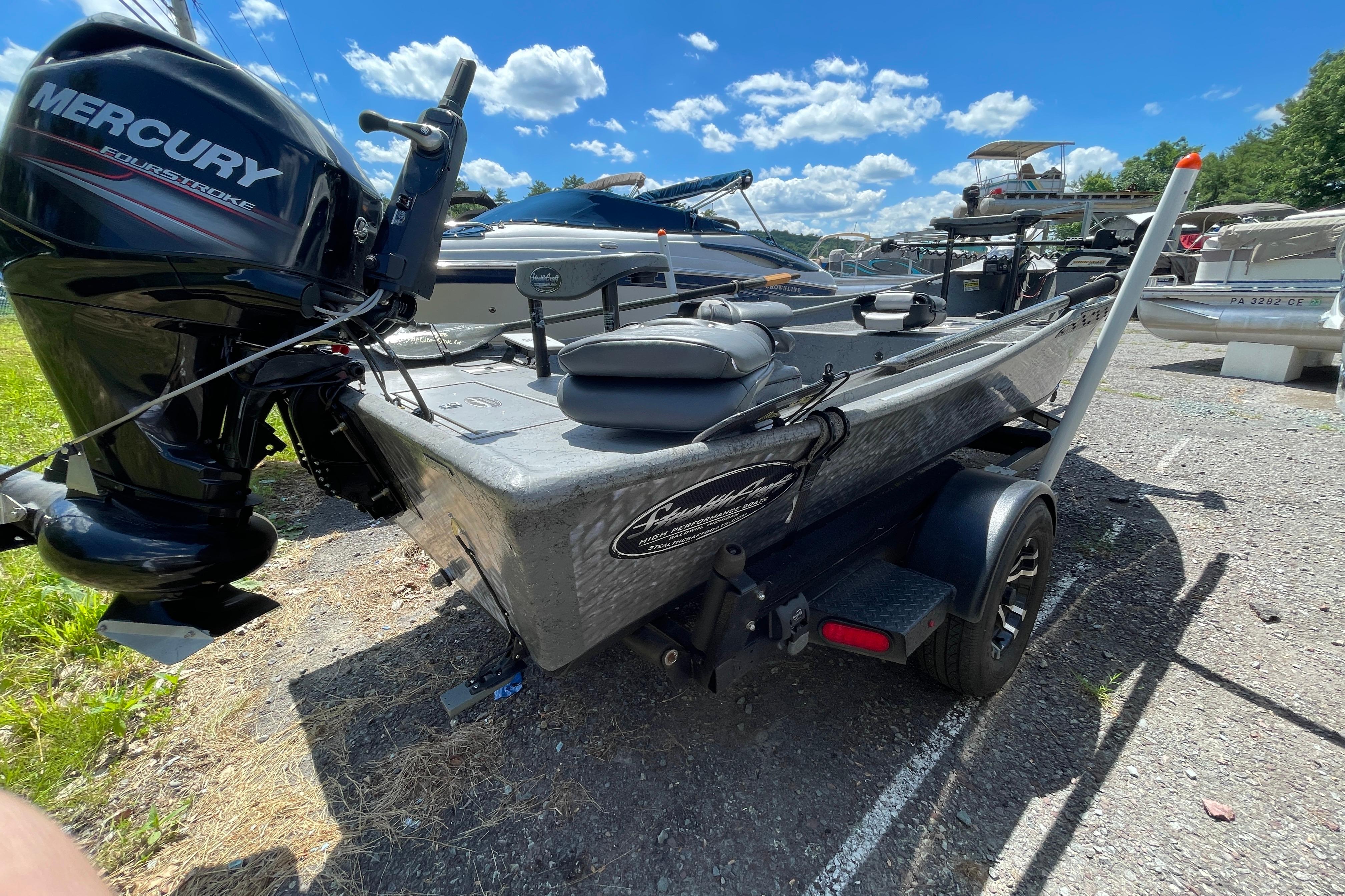 2018 StealthCraft 16 Power Drifter boat with Mercury engine, parked outdoors under blue sky.