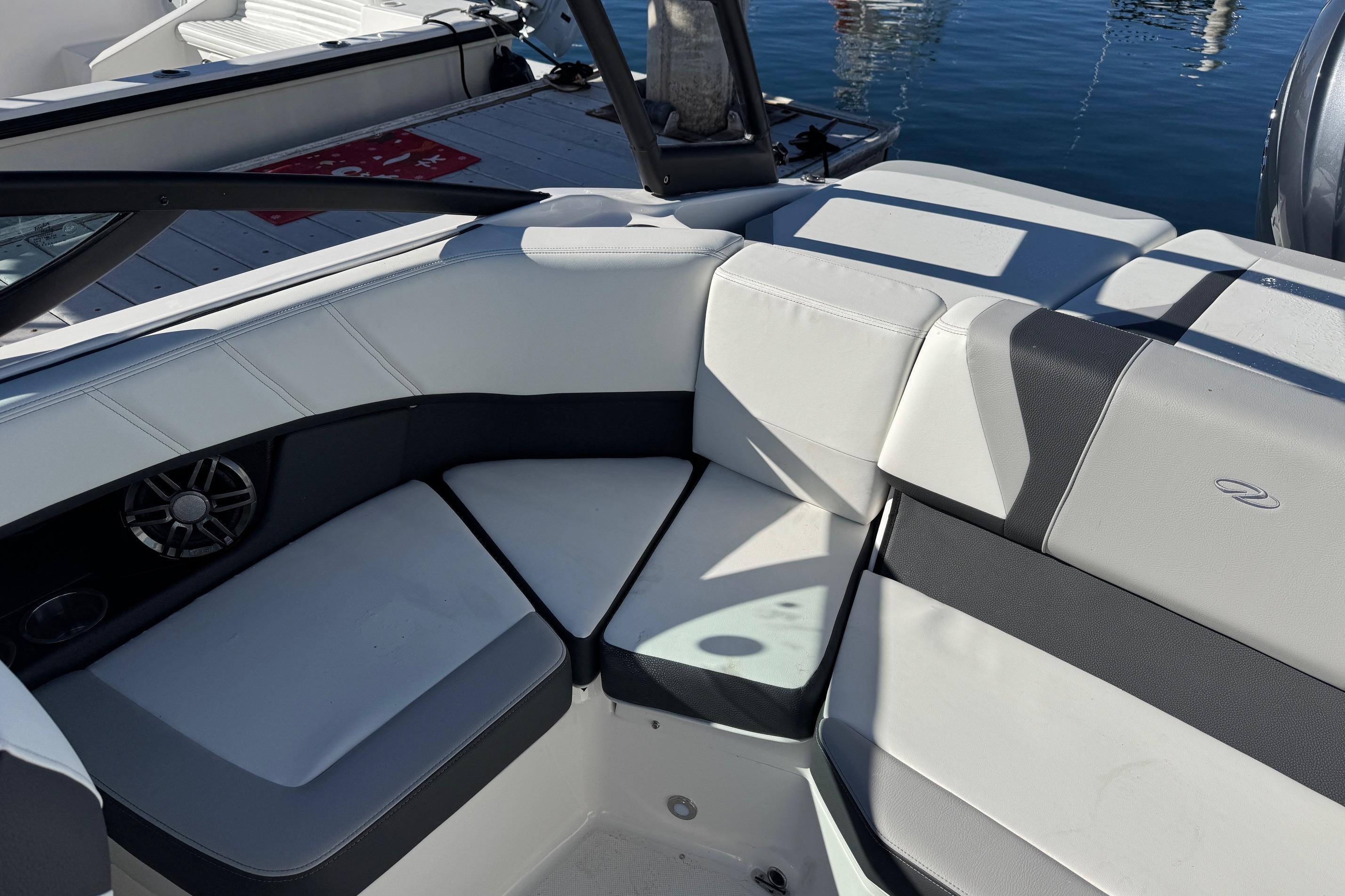2026 Regal 21 OBX boat interior with cushioned seating and speaker, docked by water.
