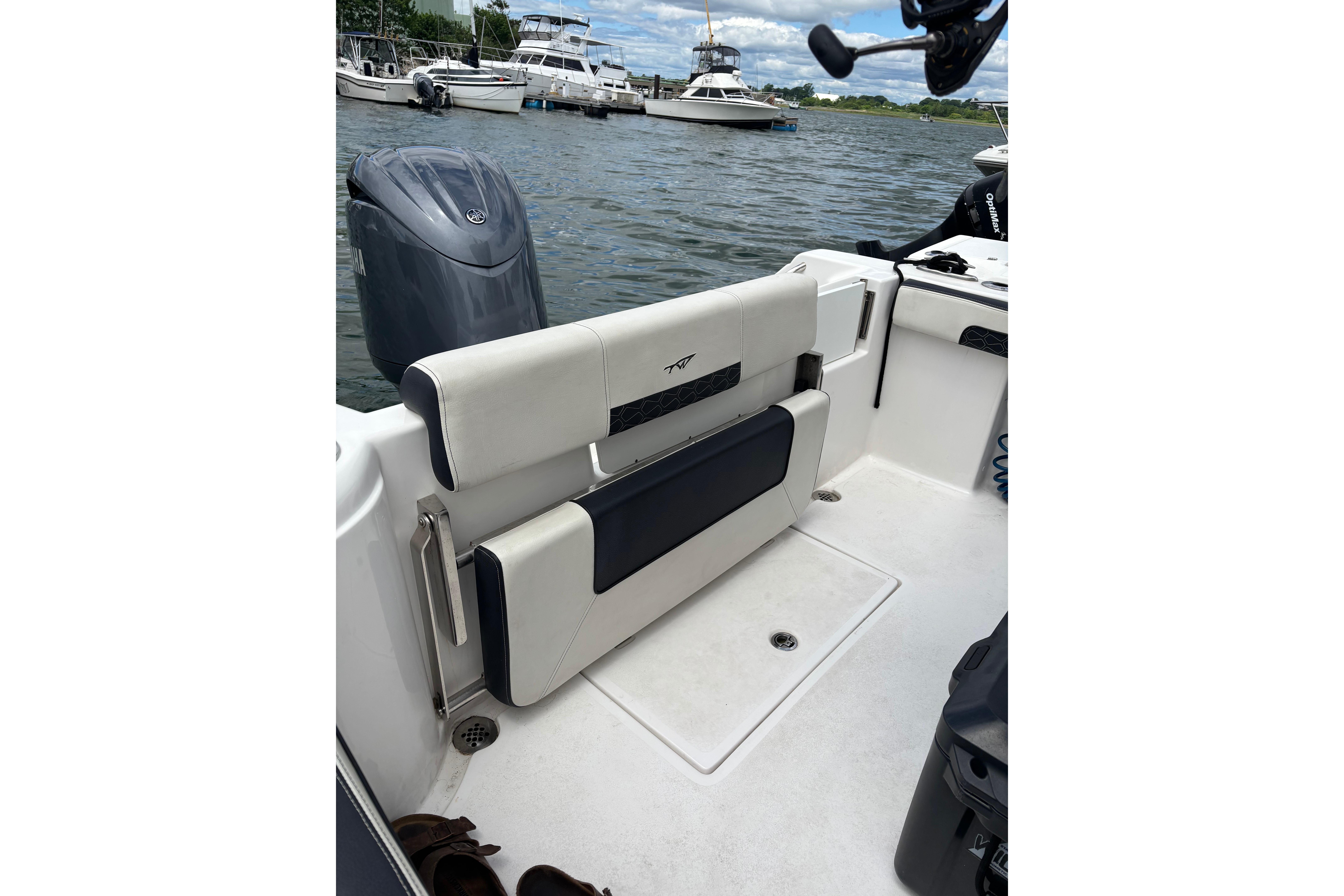 2024 Tidewater 220 CC Adventure boat interior with seating and motor, docked on a calm waterway.
