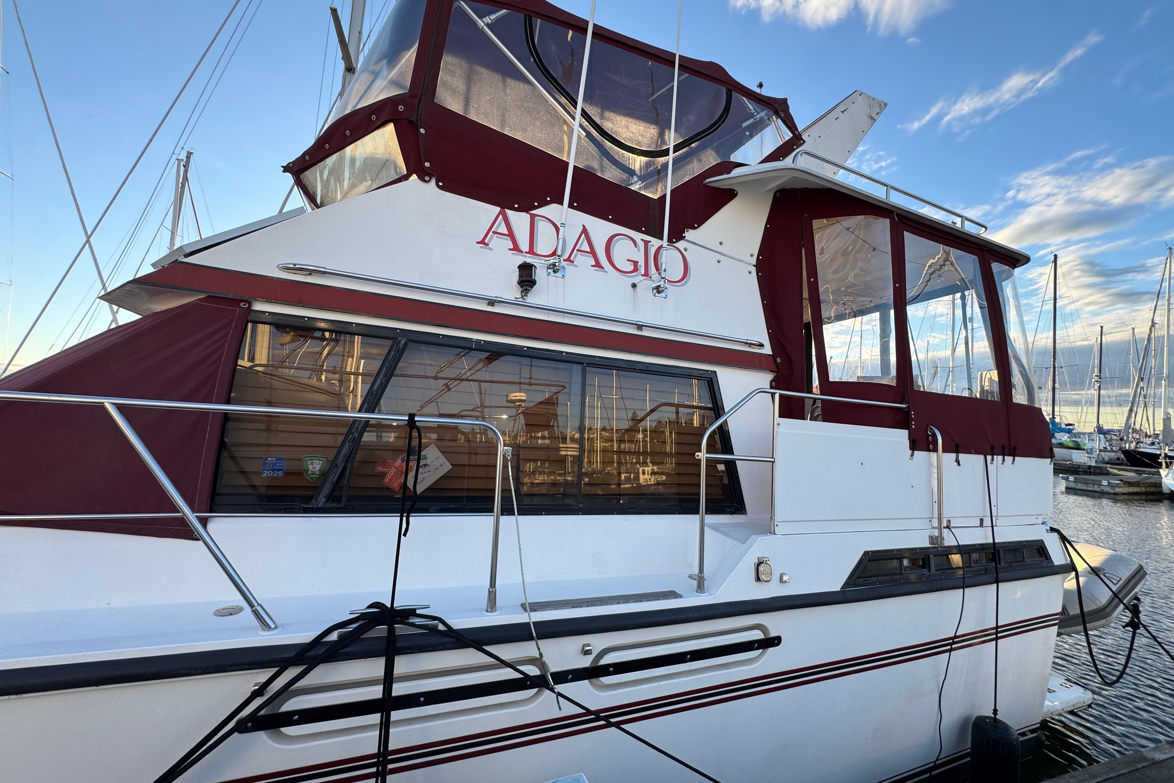 1987 President 37 yacht "Adagio" docked at marina with red accents and clear skies.