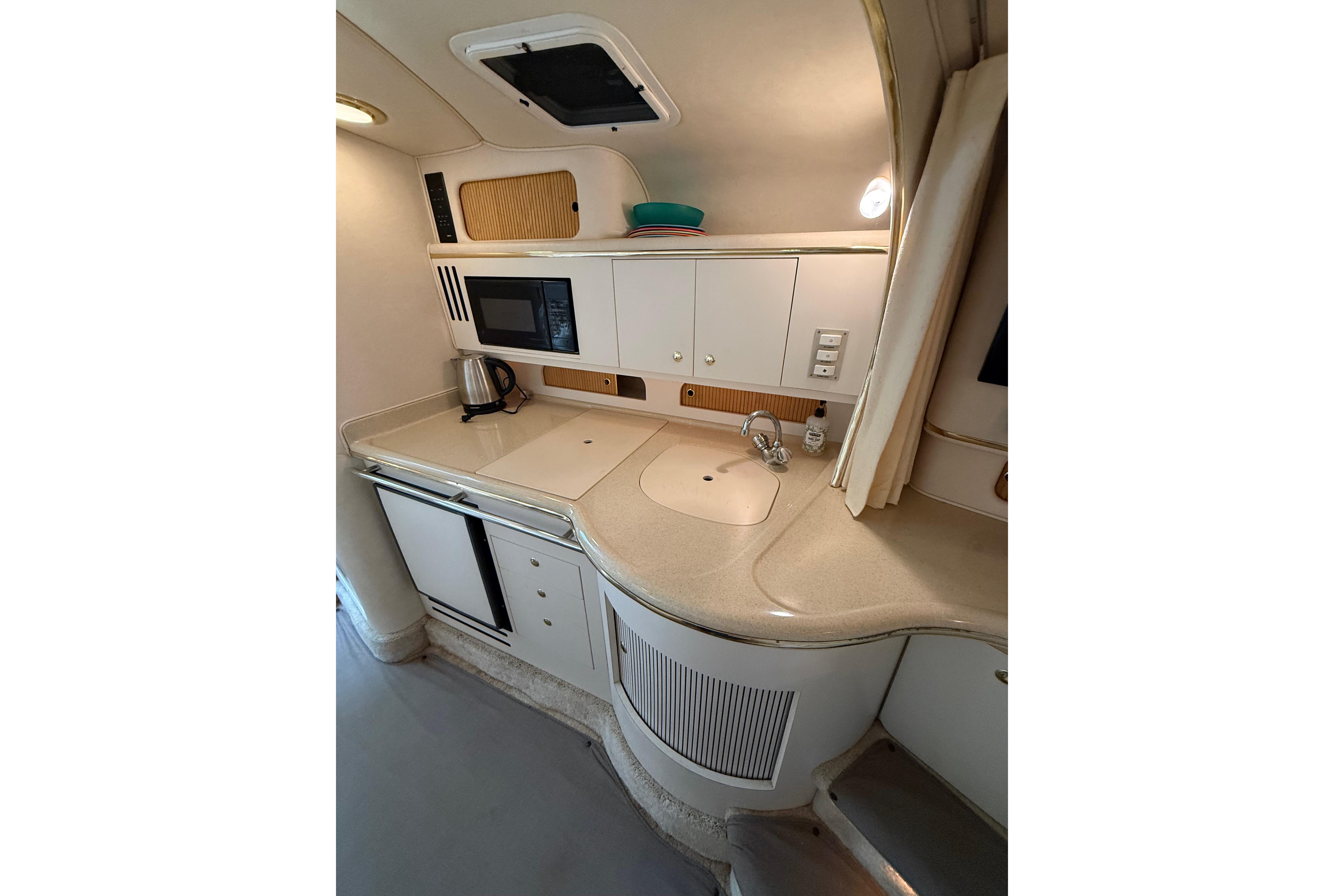 1999 Sea Ray Sundancer 310 yacht kitchen with sink, microwave, and storage cabinets.