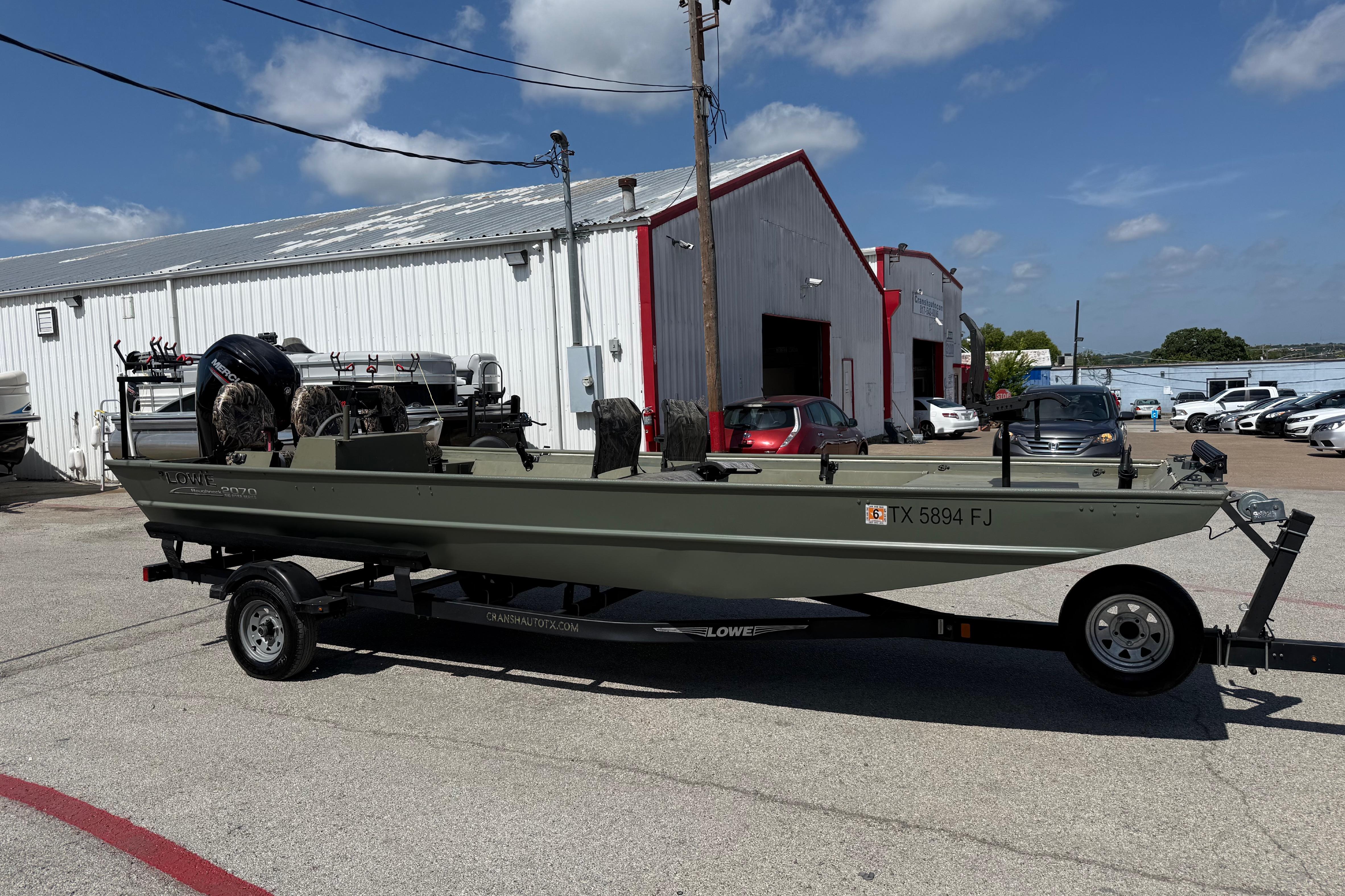 A 2020 Lowe Roughneck 2070 Big River boat on a trailer in a parking lot.