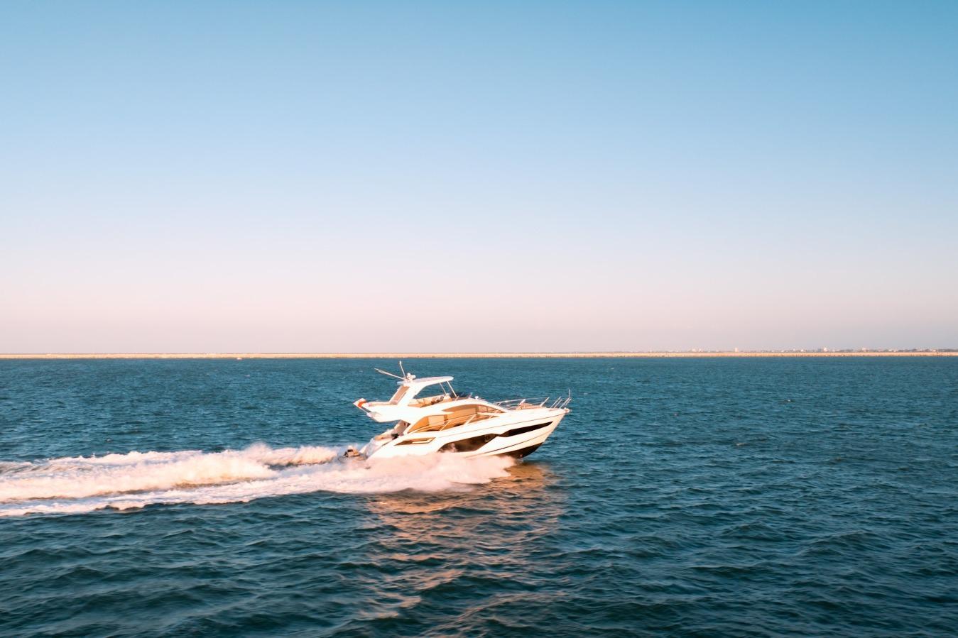 2024 Sunseeker Manhattan 55 yacht cruising on open sea under clear blue sky.