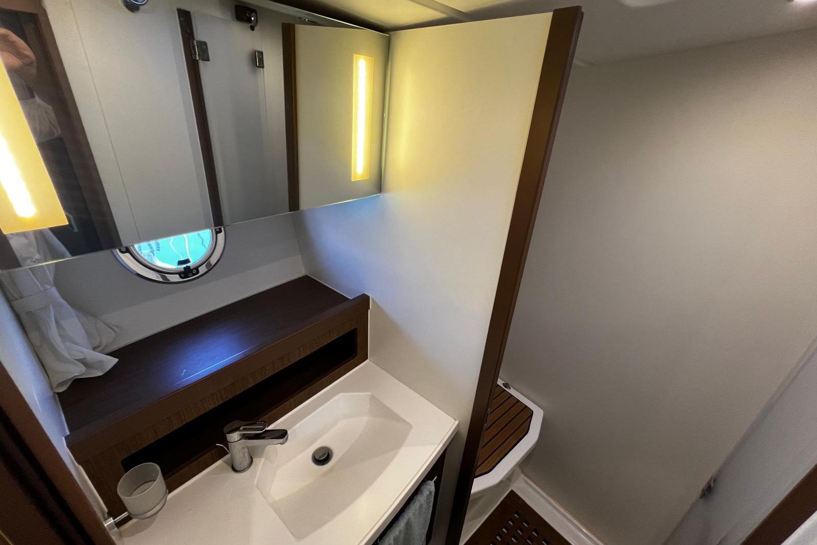 Bathroom interior of 2017 Beneteau Swift Trawler 44 with modern fixtures and porthole window.