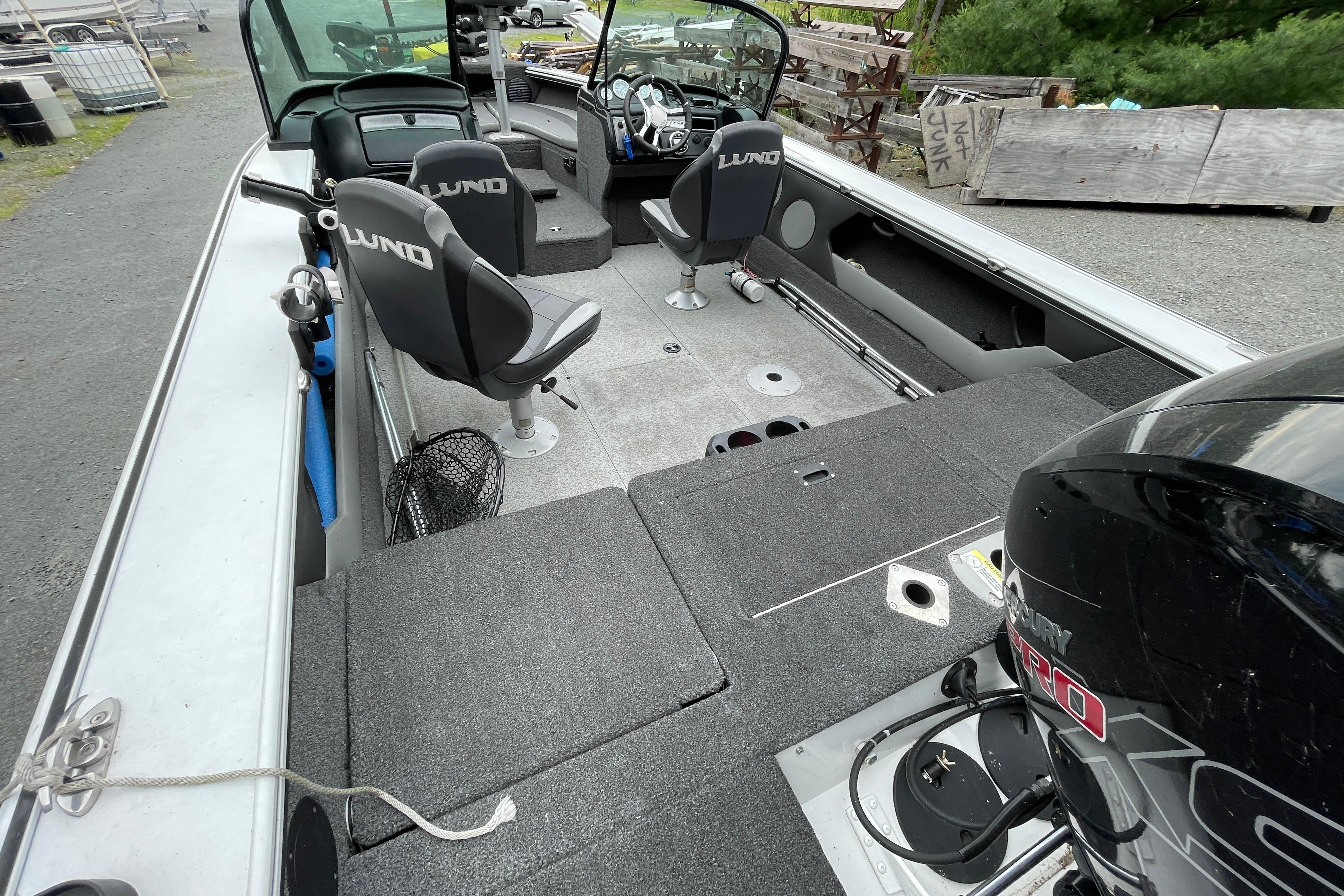 2022 Lund 1875 Crossover XS boat interior with seating and motor, parked outdoors.