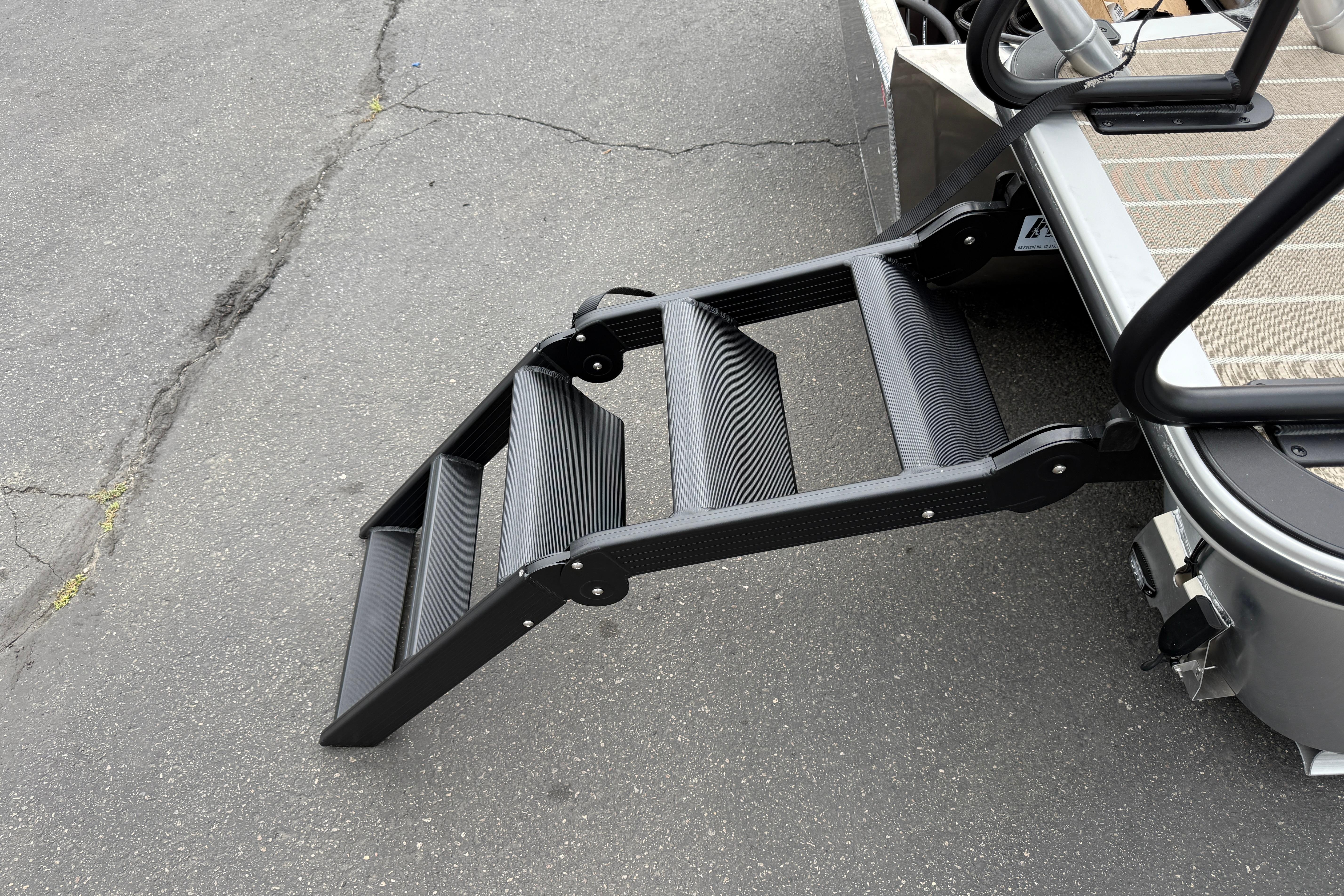 2026 Bentley Pontoons Elite 253 Admiral with extended boarding ladder on pavement.