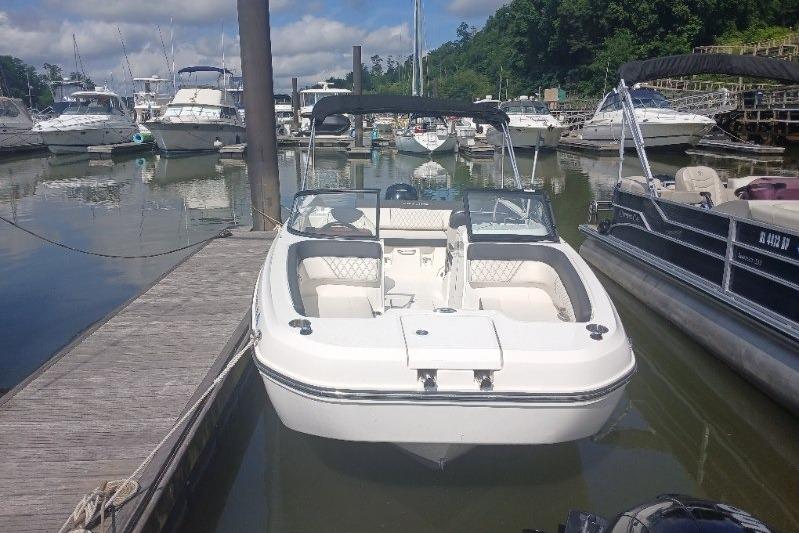 2023 Bayliner DX 2200 boat docked at a marina with other vessels.