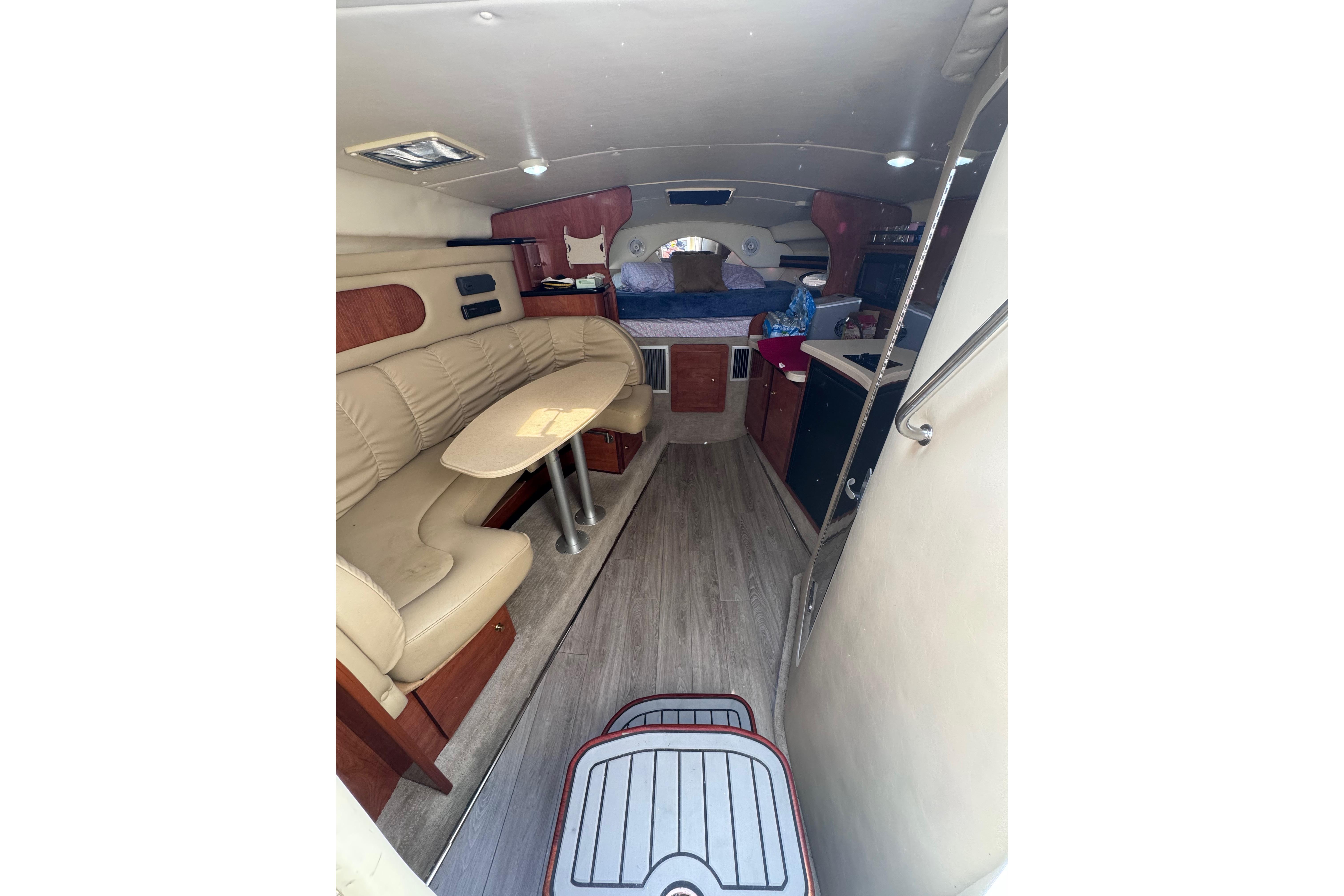 2003 Rinker Fiesta Vee 312 cabin interior with seating, table, and kitchenette.