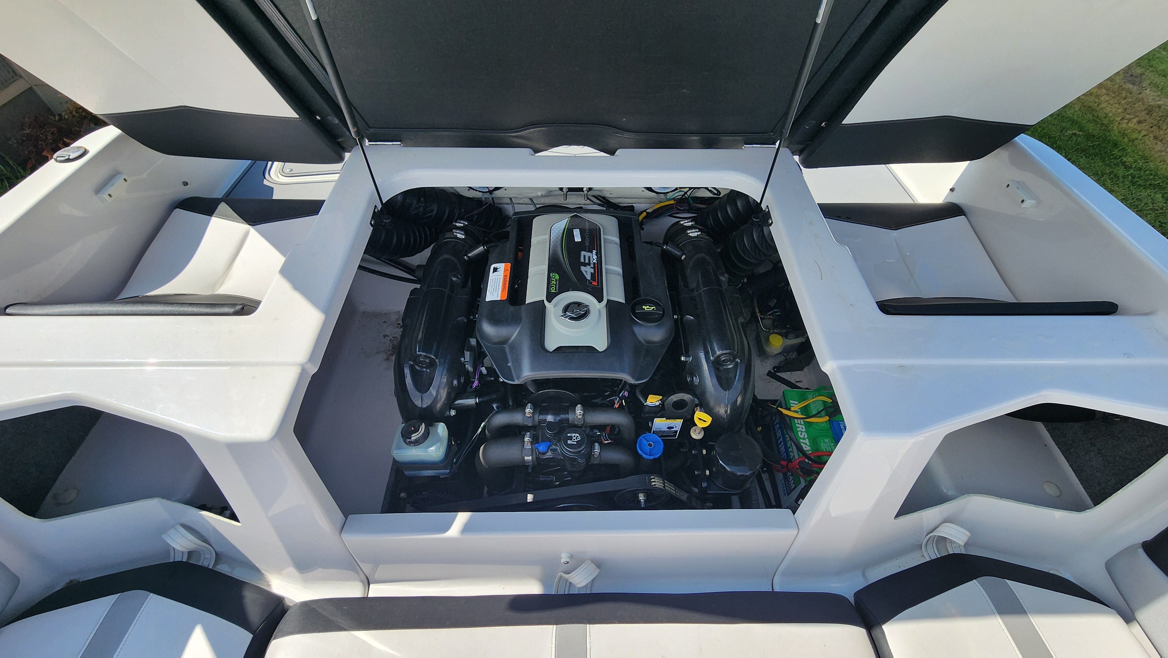 The engine compartment of a 2015 Four Winns H190 is open, revealing the engine and wiring.