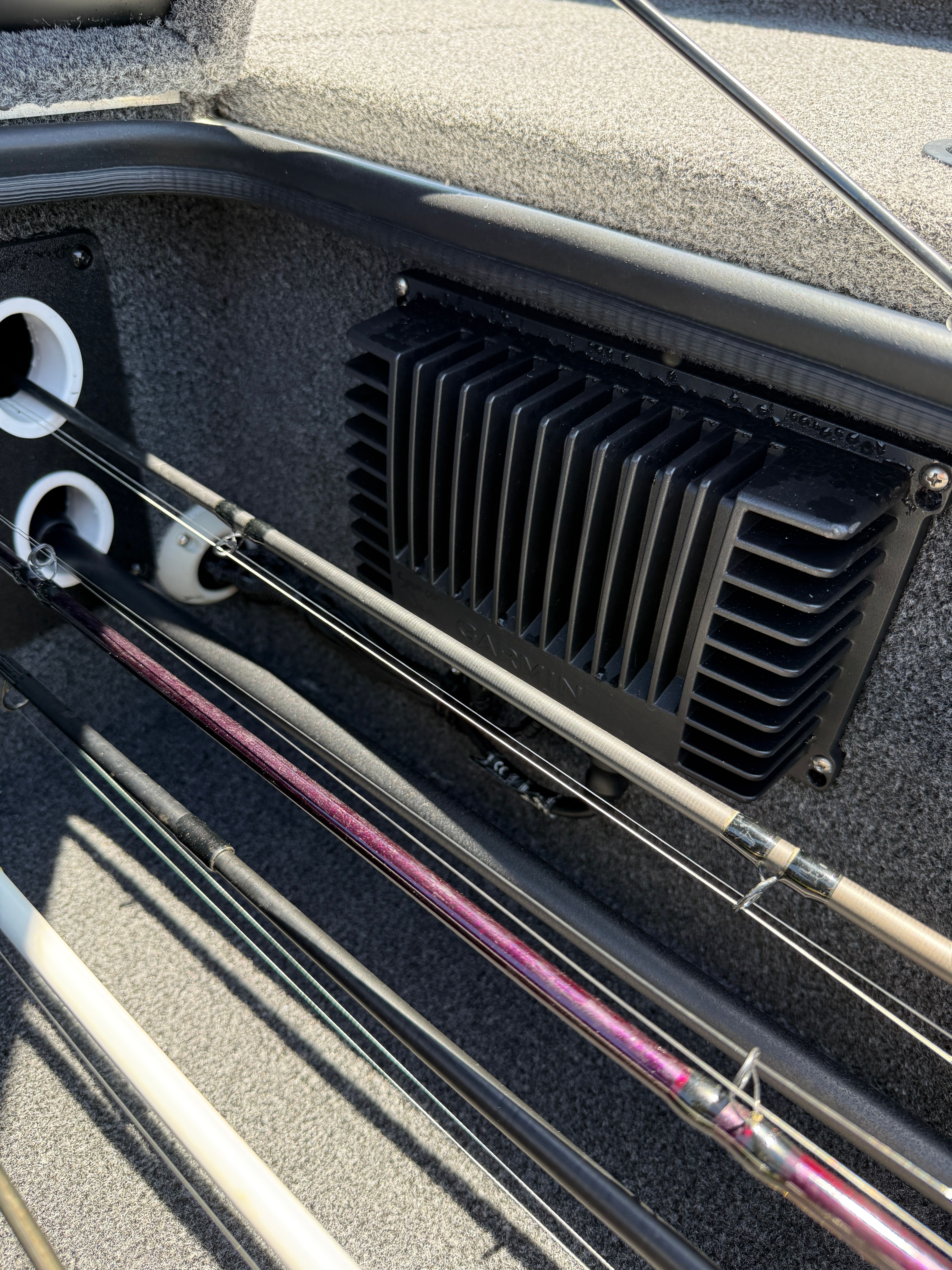 Fishing rods in a boat storage compartment with a vent grille.