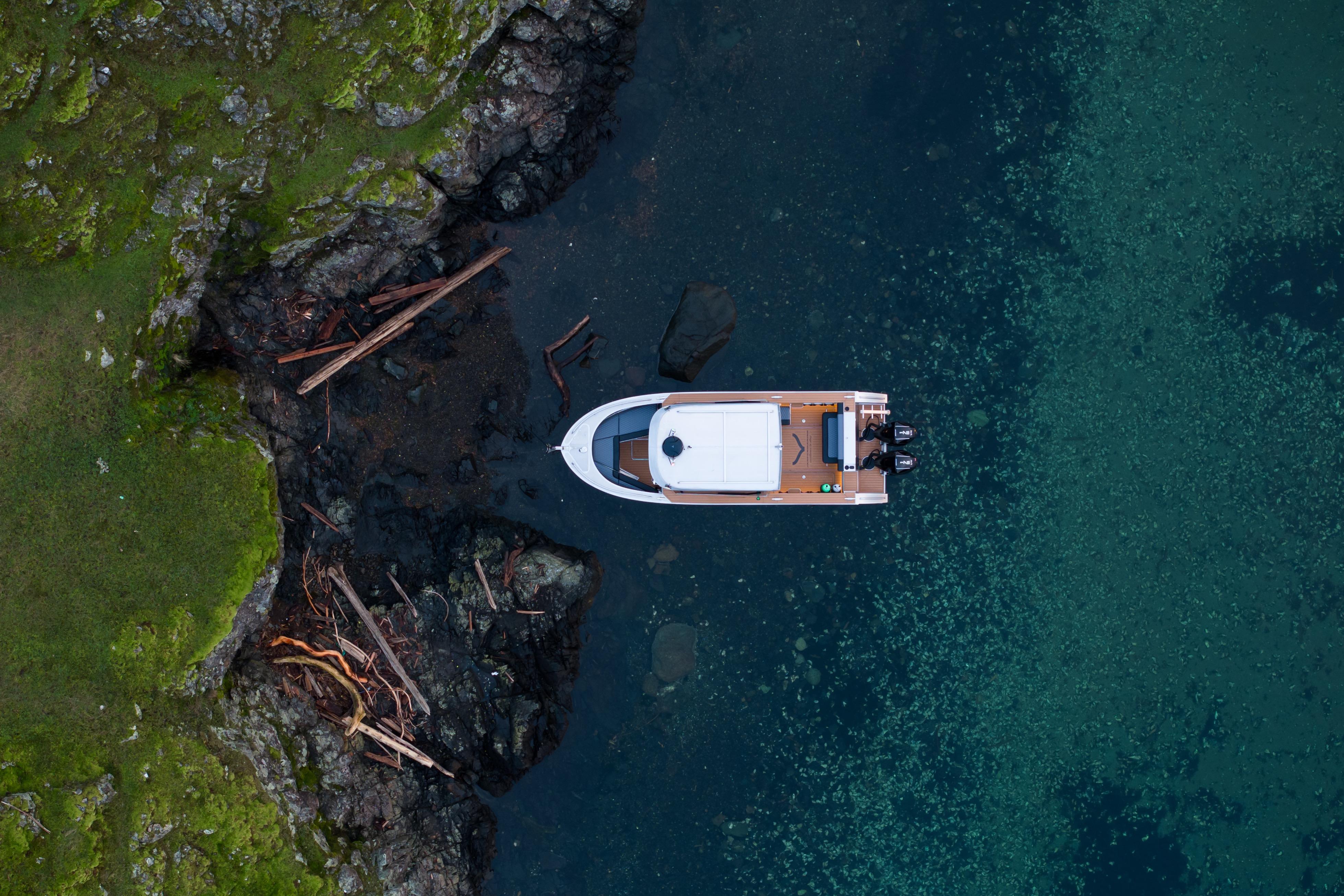 Aerial view of 2026 Jasper Marine Defender 22 boat near rocky shoreline.