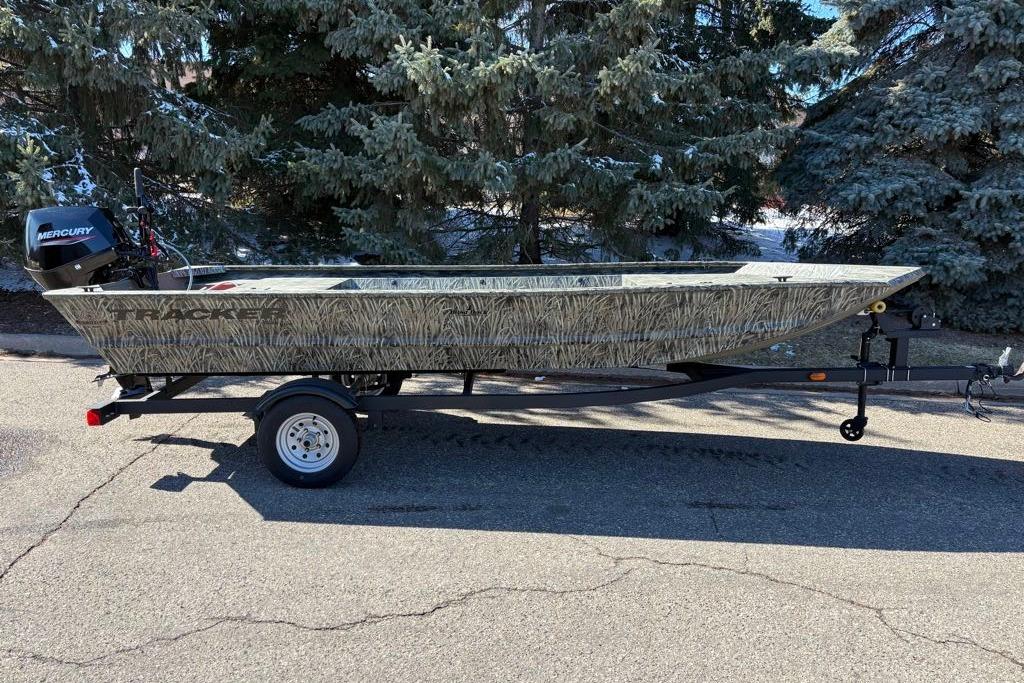 2026 Tracker Grizzly 1648 Utility boat on trailer, parked near trees.