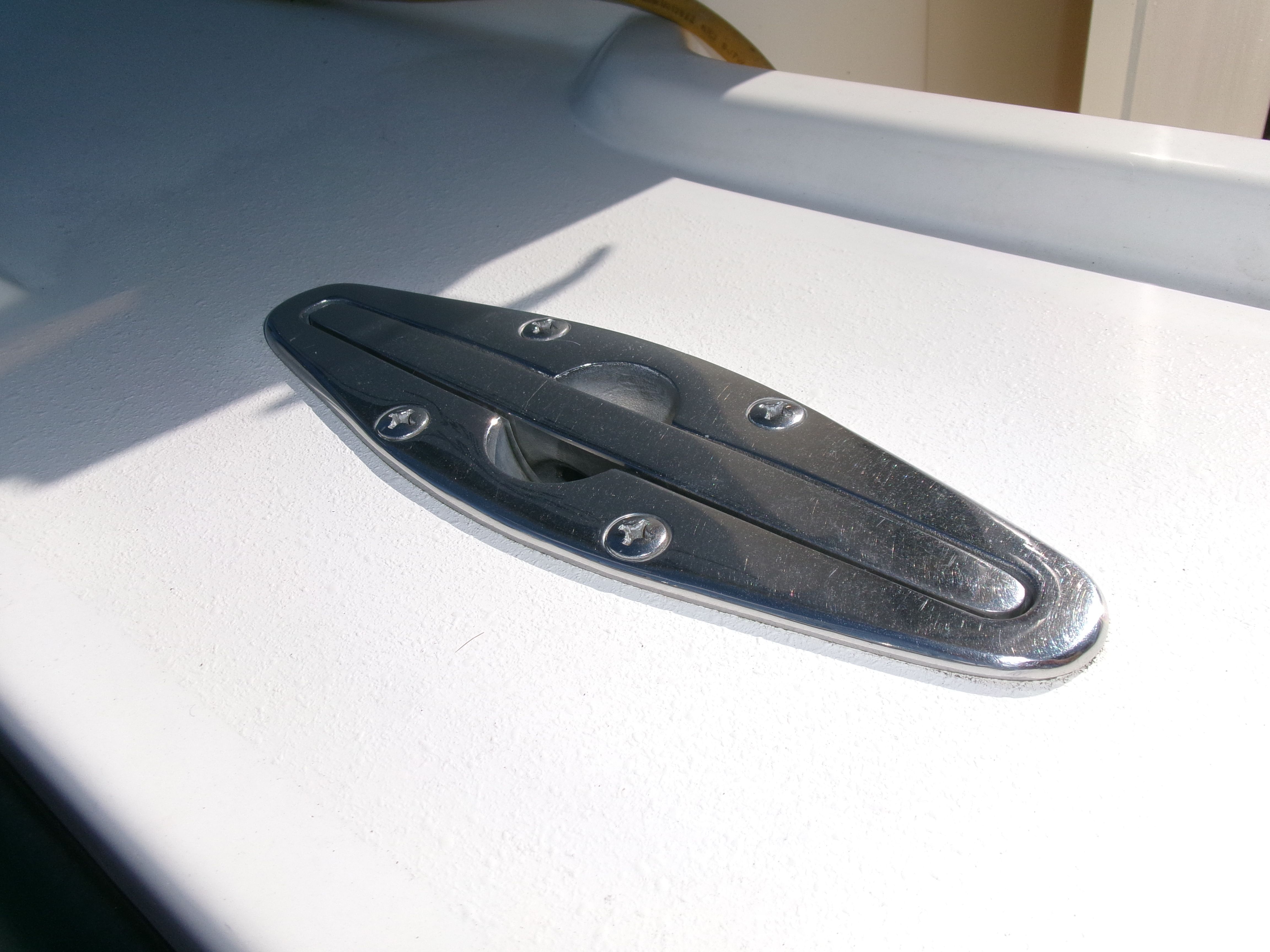 Close-up of a silver boat cleat on a white deck.