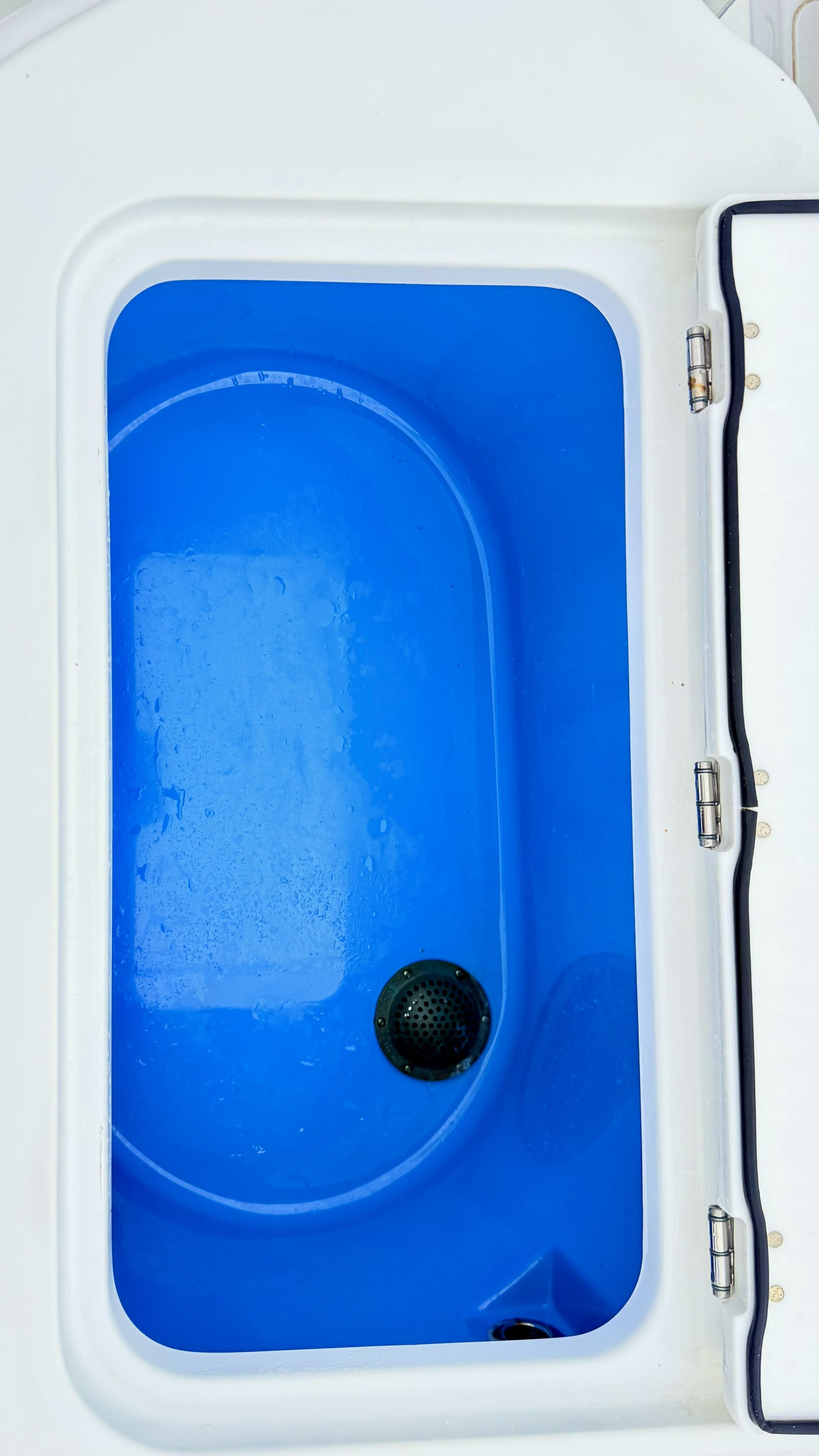A blue, oval container with a drain inside a boat.