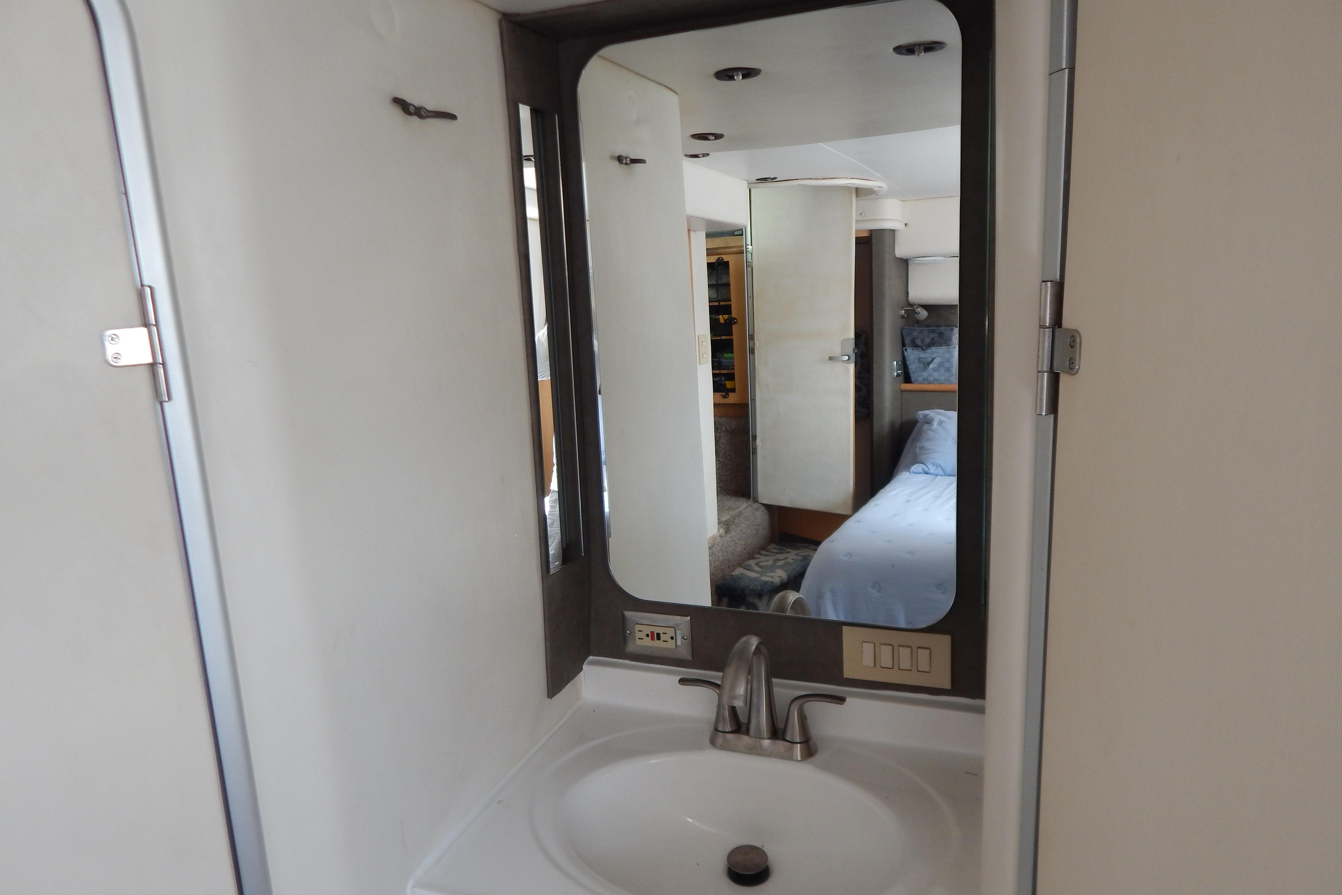 Interior of 1998 Magnum 4100 SCR showing bathroom sink and mirror reflection.