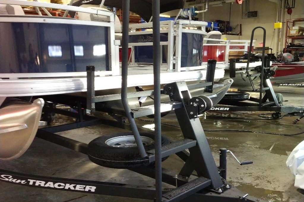 2026 Sun Tracker Bass Buggy 18 DLX pontoon boat on trailer in a garage.