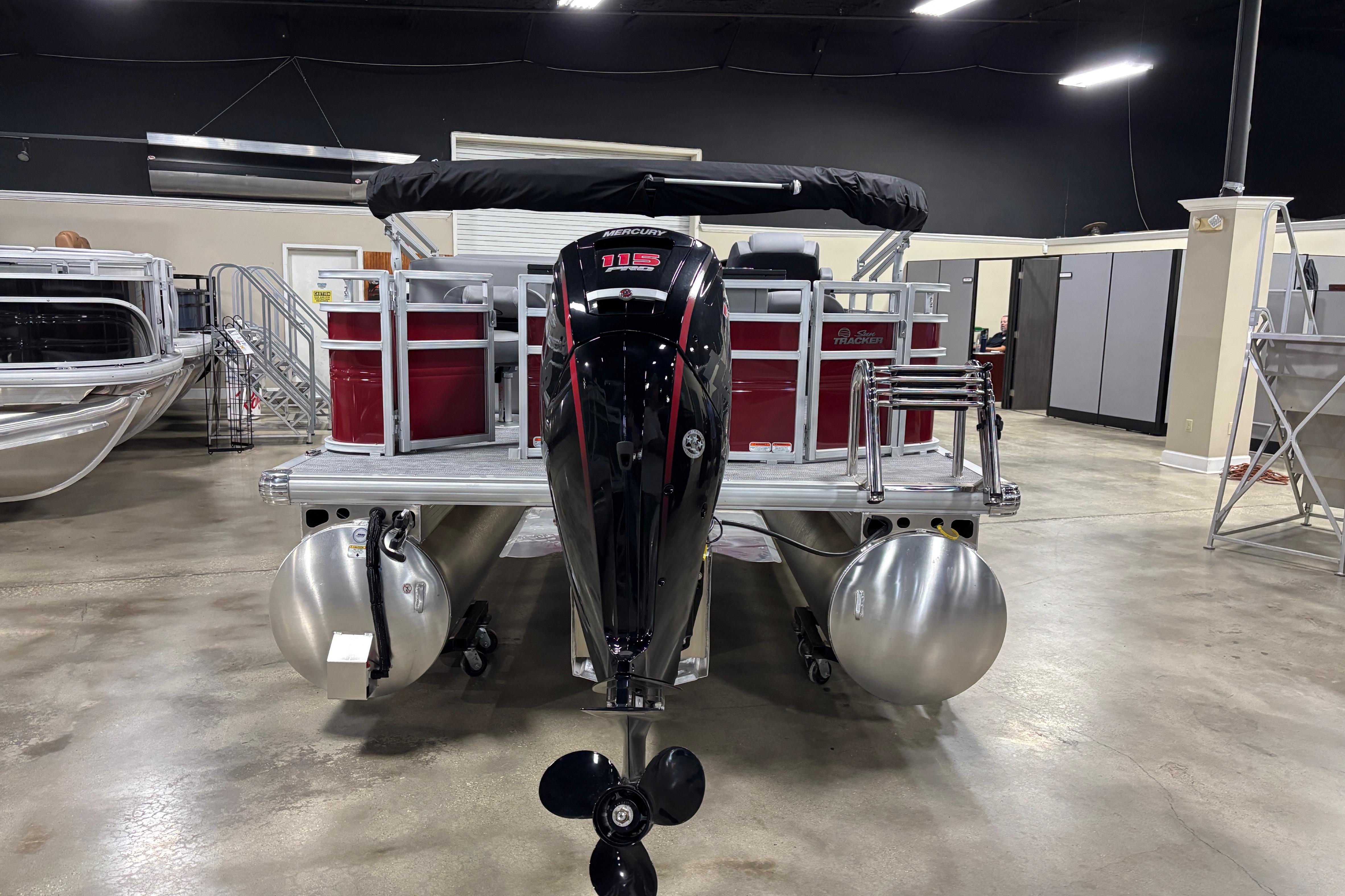 2026 Sun Tracker SportFish 20 DLX pontoon boat with Mercury 115 outboard motor in showroom.