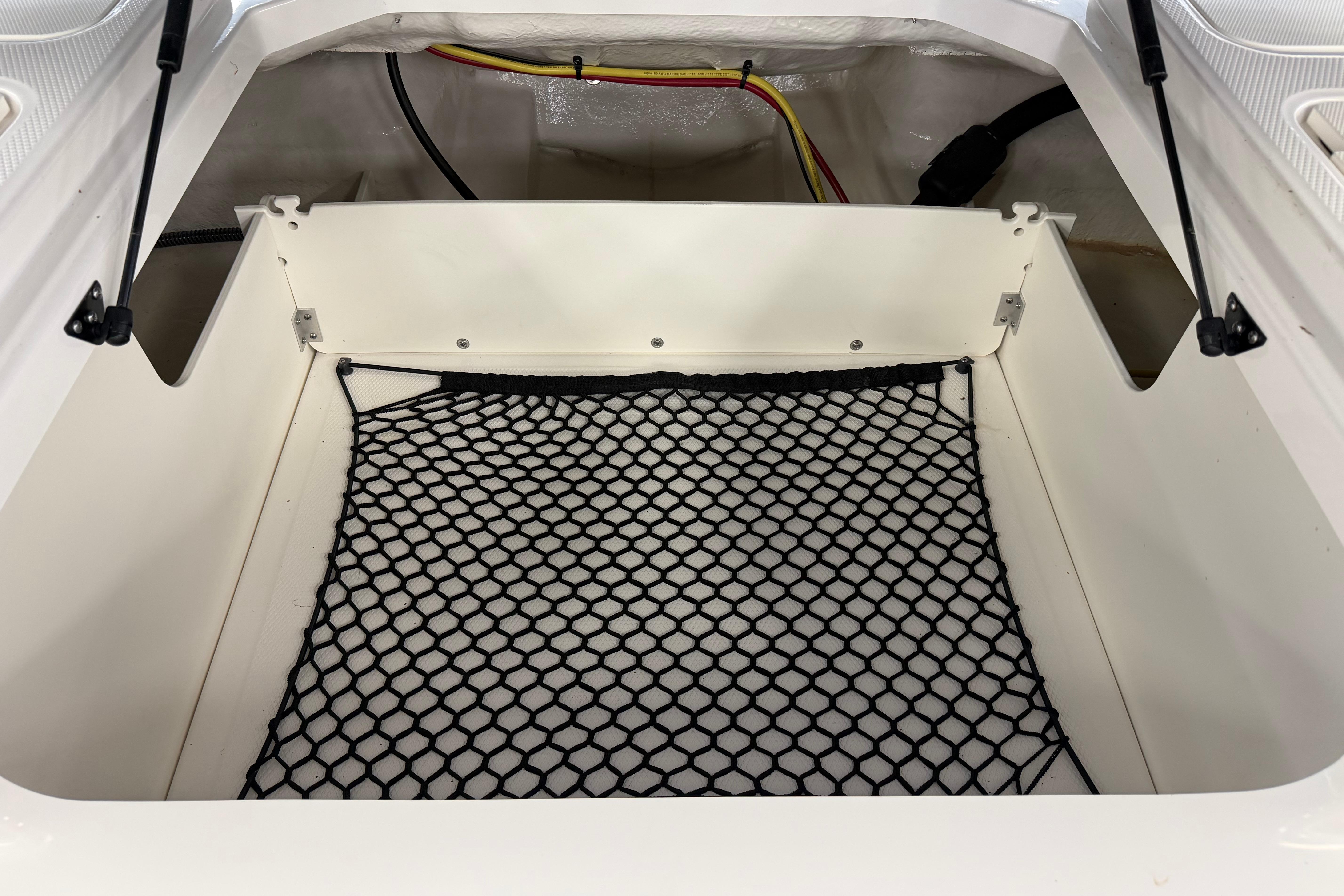 2025 Chaparral 21 SSi OB storage compartment with netting and wiring.