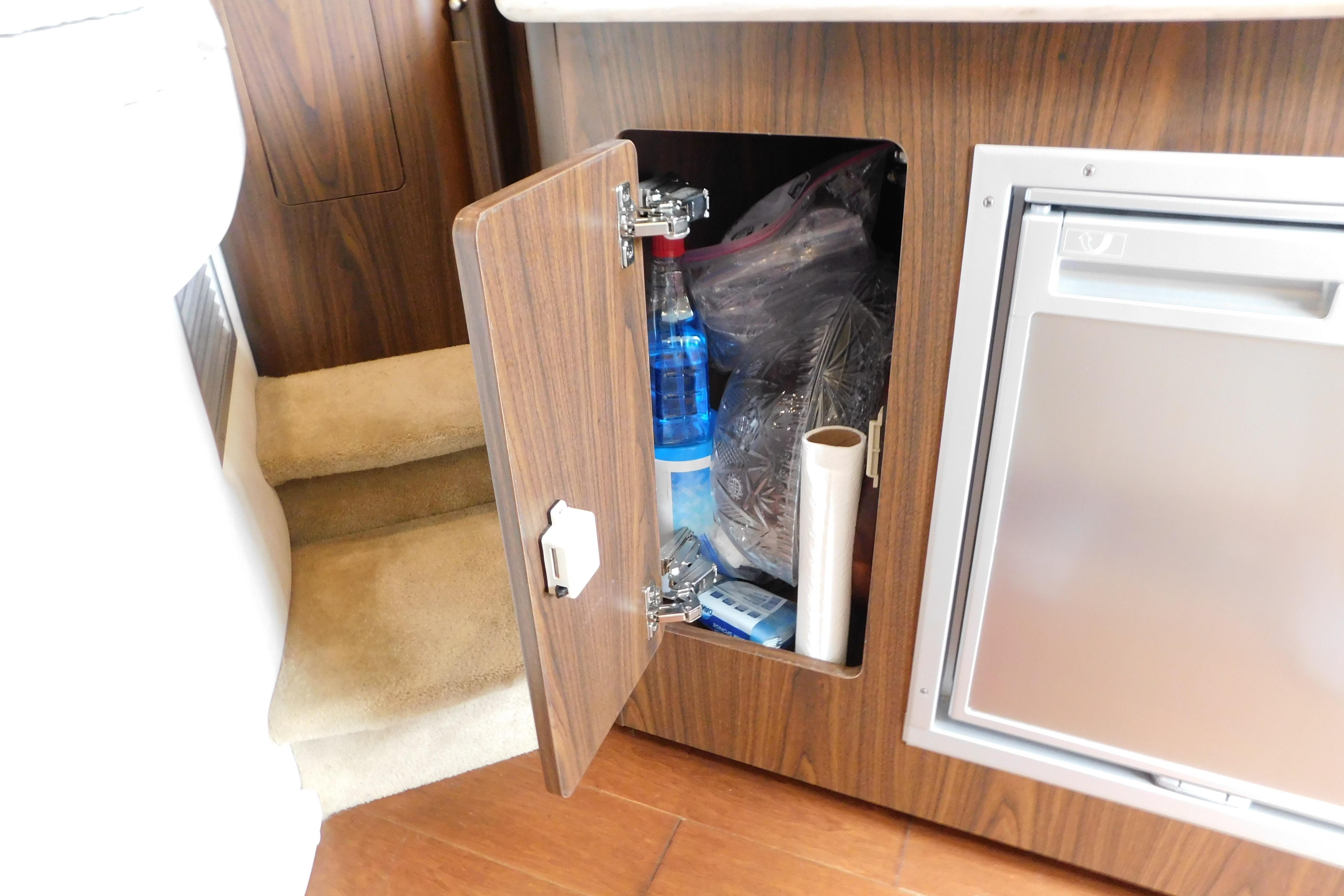 Open cabinet in 2017 Rinker EX 320 boat interior, revealing storage items.