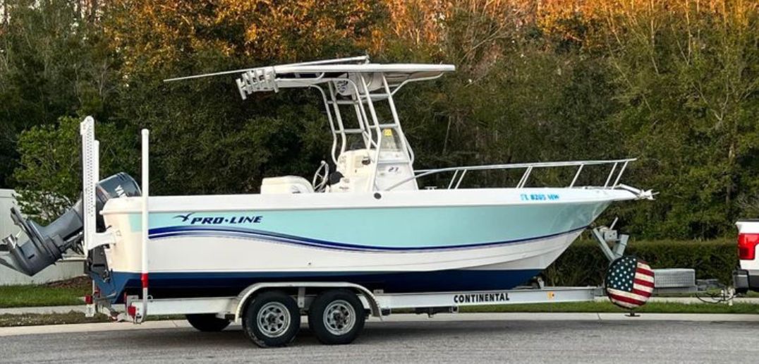 A 2005 Pro-Line 23 Sport boat on a trailer, surrounded by trees.