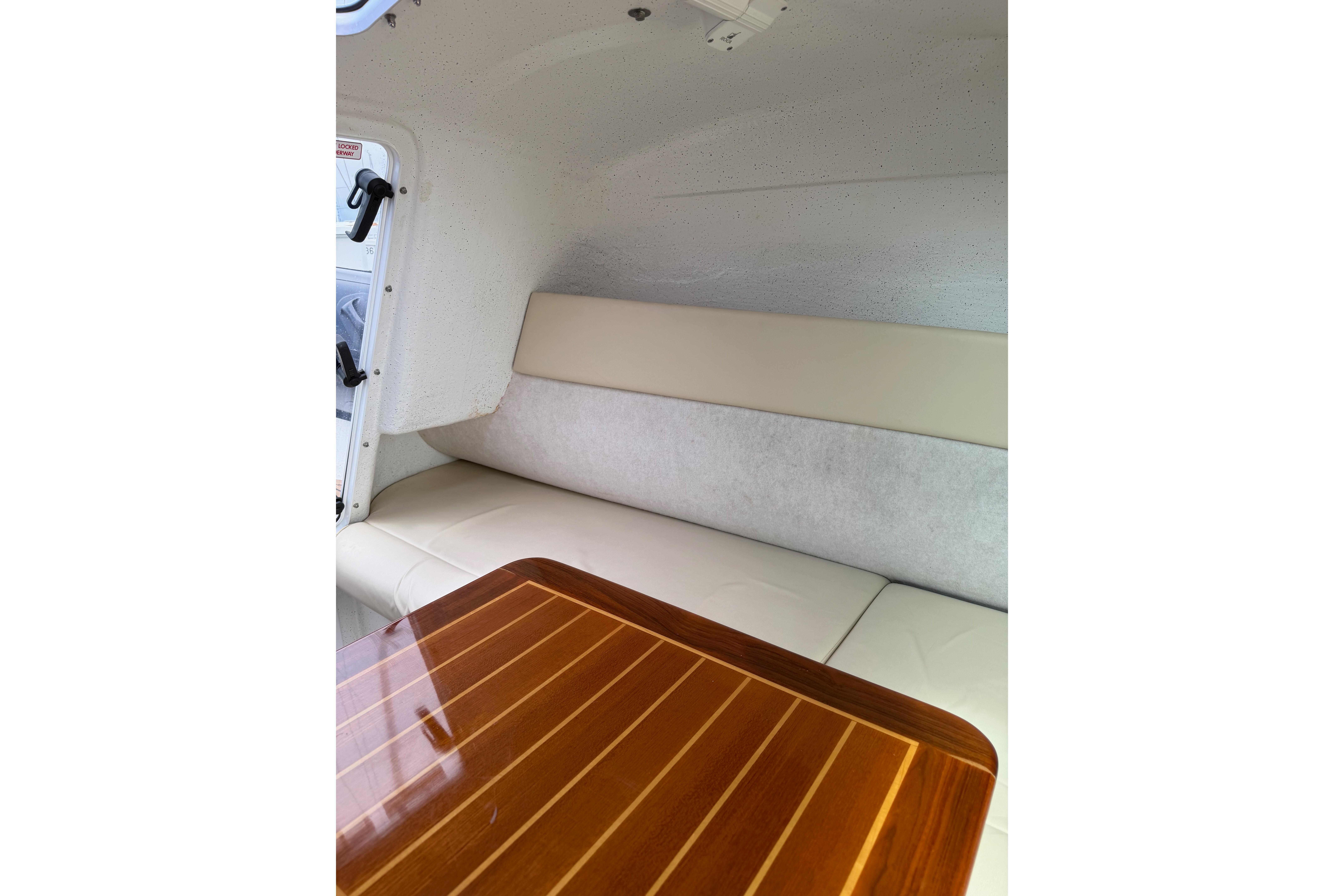 Interior of 2016 Protector Targa 30 boat with cushioned seating and wooden table.